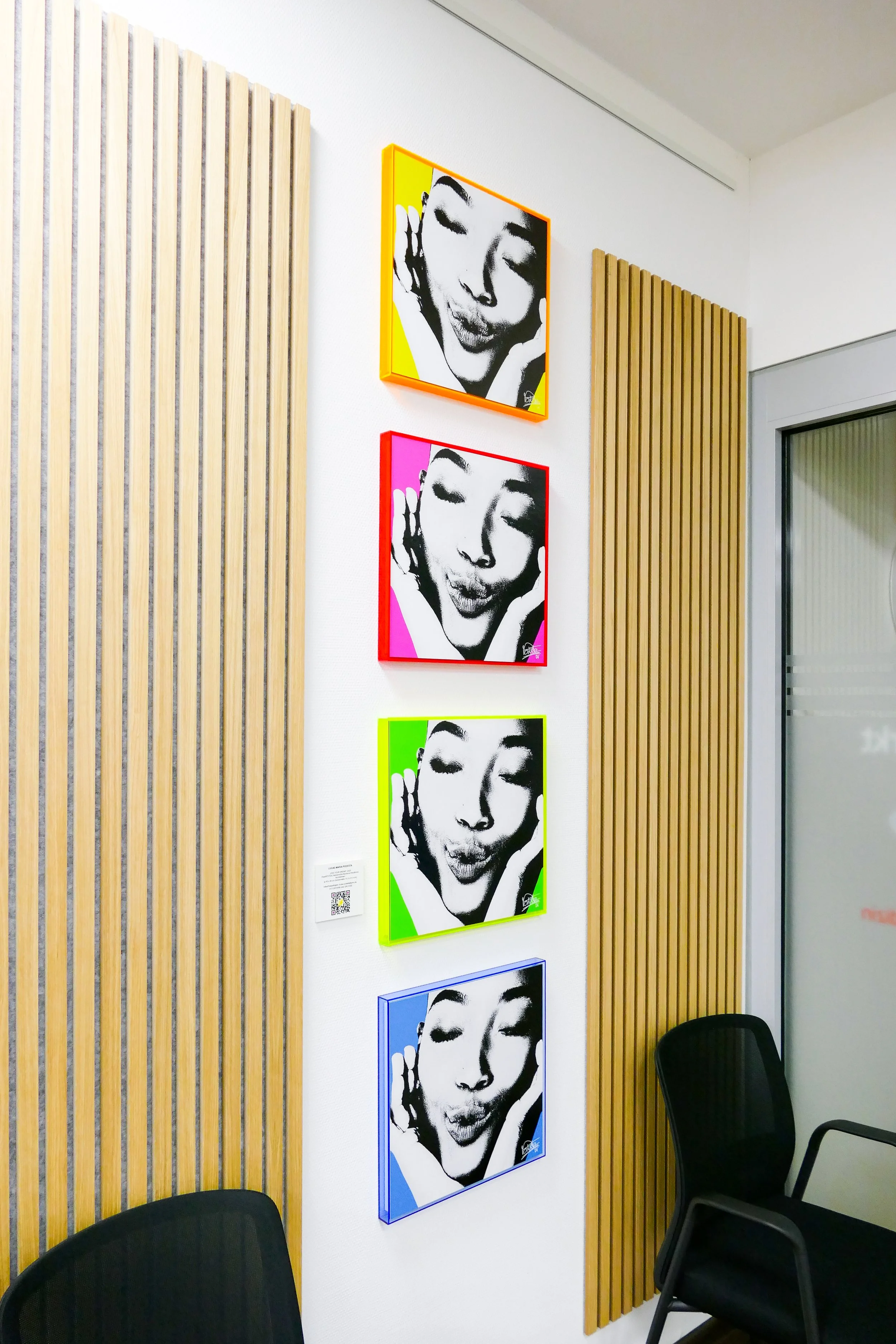 Vier bunte Bilder in Pop-Art-Stil an einer weißen Wand, zeigen eine schwarz-weiße Porträtaufnahme einer Katze mit geschlossenen Augen, die ihre Hände an die Wangen hält, eingerahmt in gelb, rot, grün und blau.