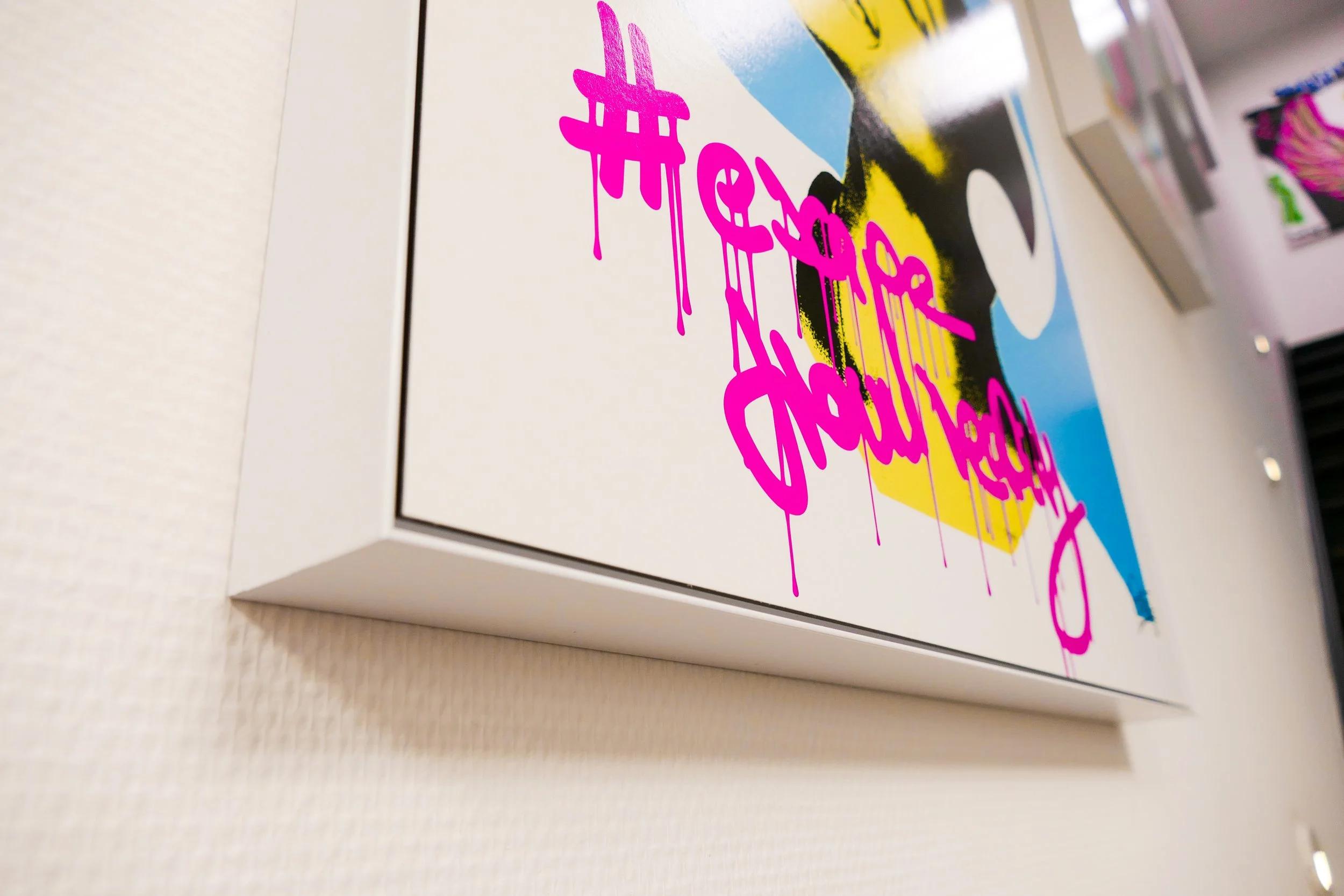 Kunstwerk mit pinkfarbenem Graffiti-Text '#escape from reality' auf einer weißen Wand.