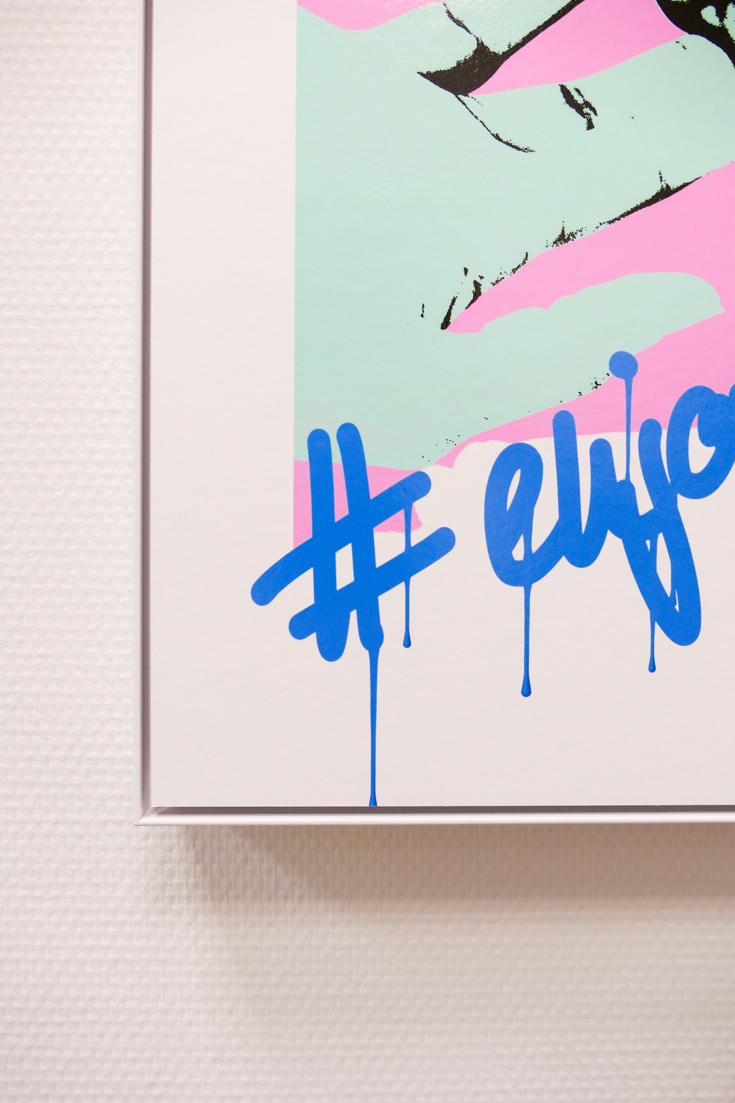 Kunstwerk mit bunten Farbflächen und blauer Graffiti-Schrift, die hashtag und das Wort 'enjoy' zeigt.
