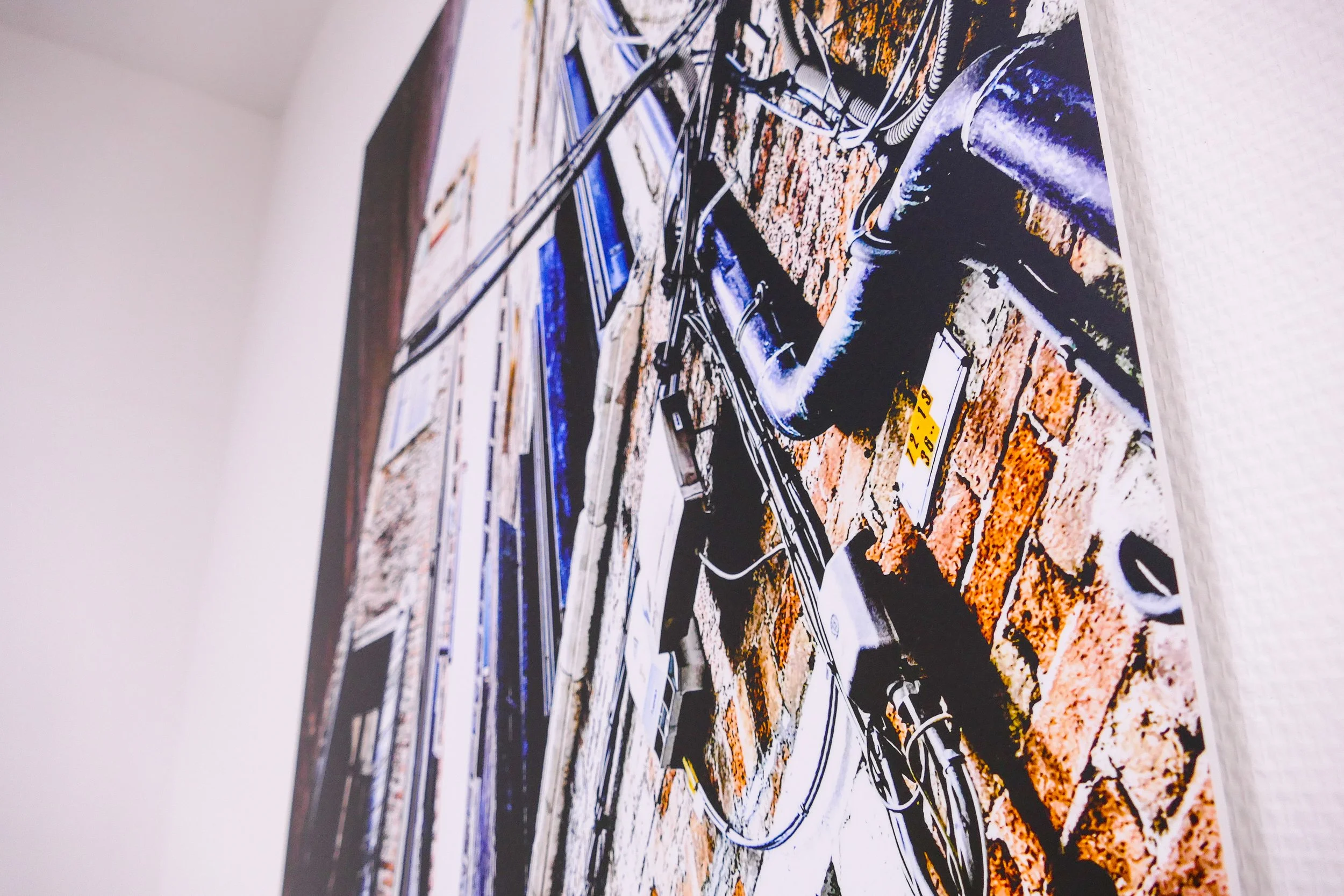 Blick auf eine Wand mit verschiedenen Kabeln, Steckdosen und technischen Geräten, teilweise an einer Backsteinmauer installiert.