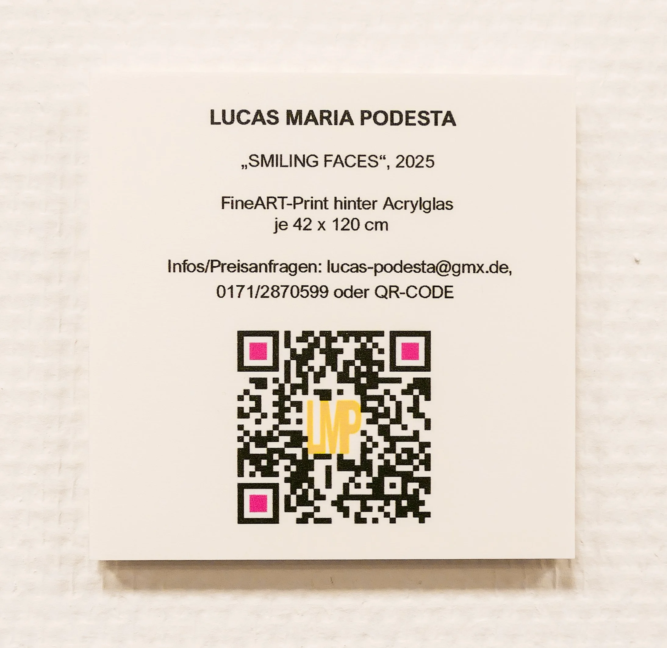 Informationstafel für das Kunstwerk "Smiling Faces" von Lucas Maria Podesta, 2025, mit QR-Code.