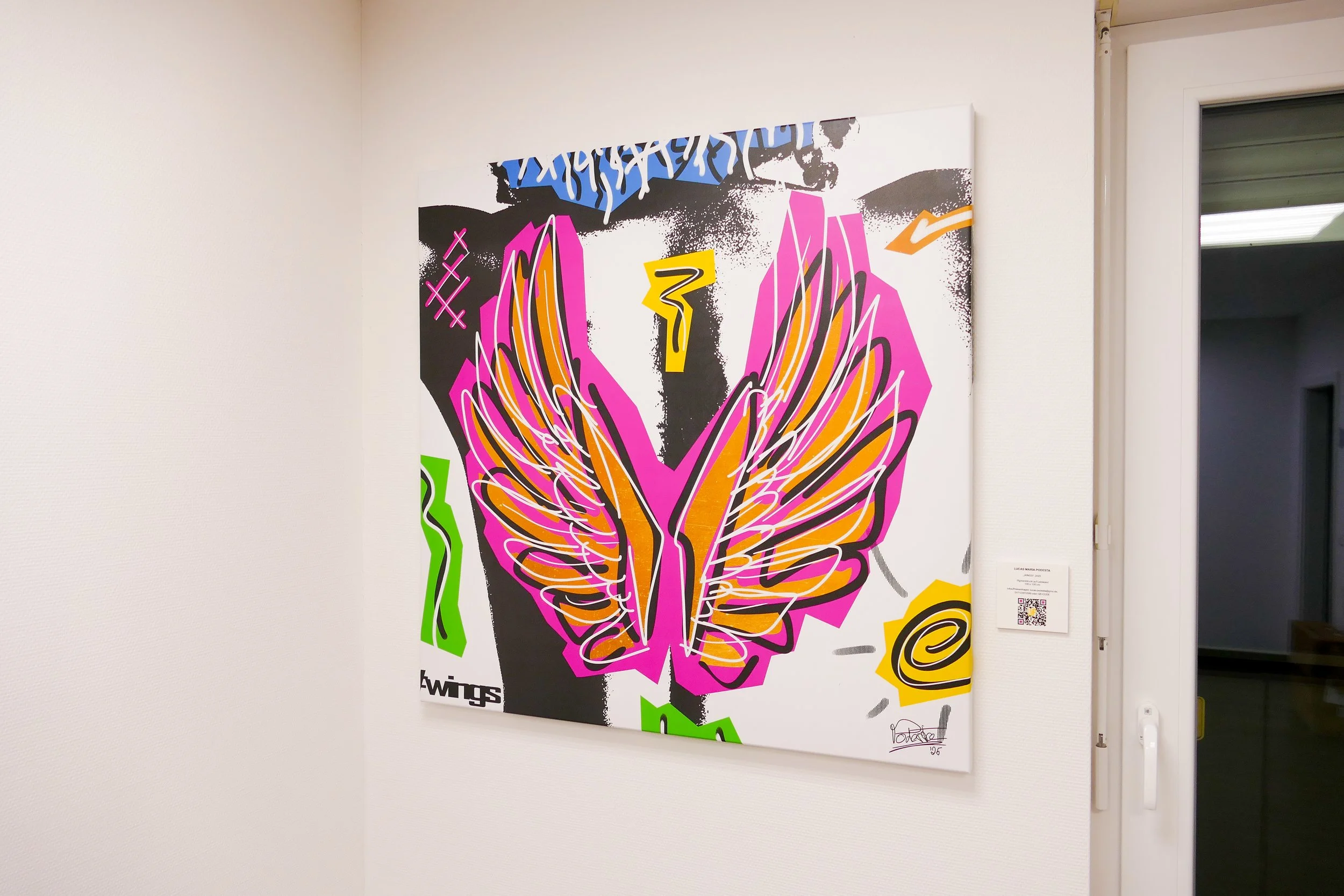 Ein buntes Street-Art-Gemälde einer stilisierten Schmetterlingsfigur mit pinken, orange, und schwarzen Linien auf einer weißen Leinwand, angebracht an einer weißen Wand neben einer Tür.