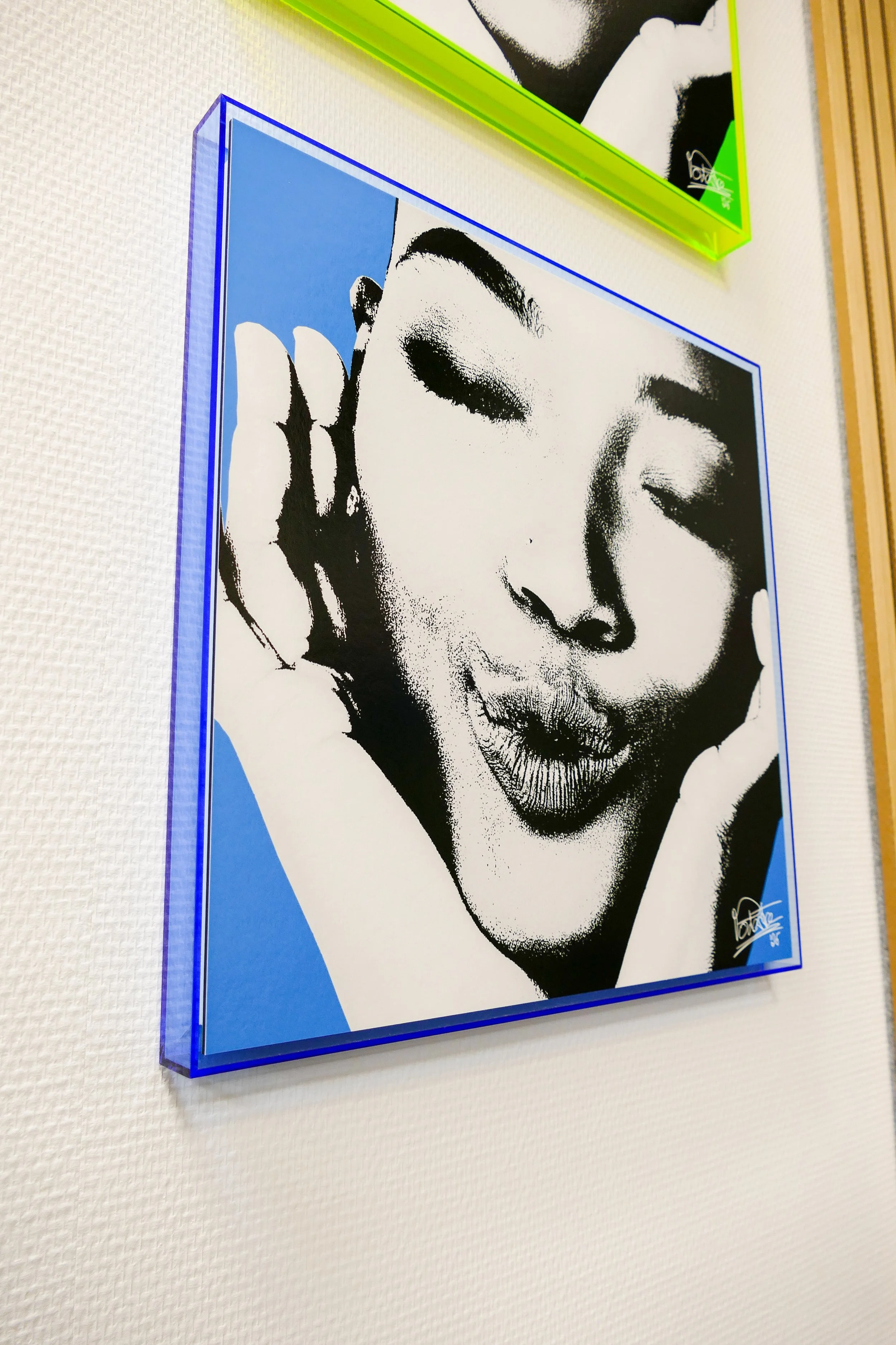 Hochwertiges Pop-Art-Porträt einer Frau mit geschlossenen Augen und leicht geöffnetem Mund, die mit den Händen die Wange berührt, in Schwarz-Weiß-Optik mit blauer und grüner Rahmen