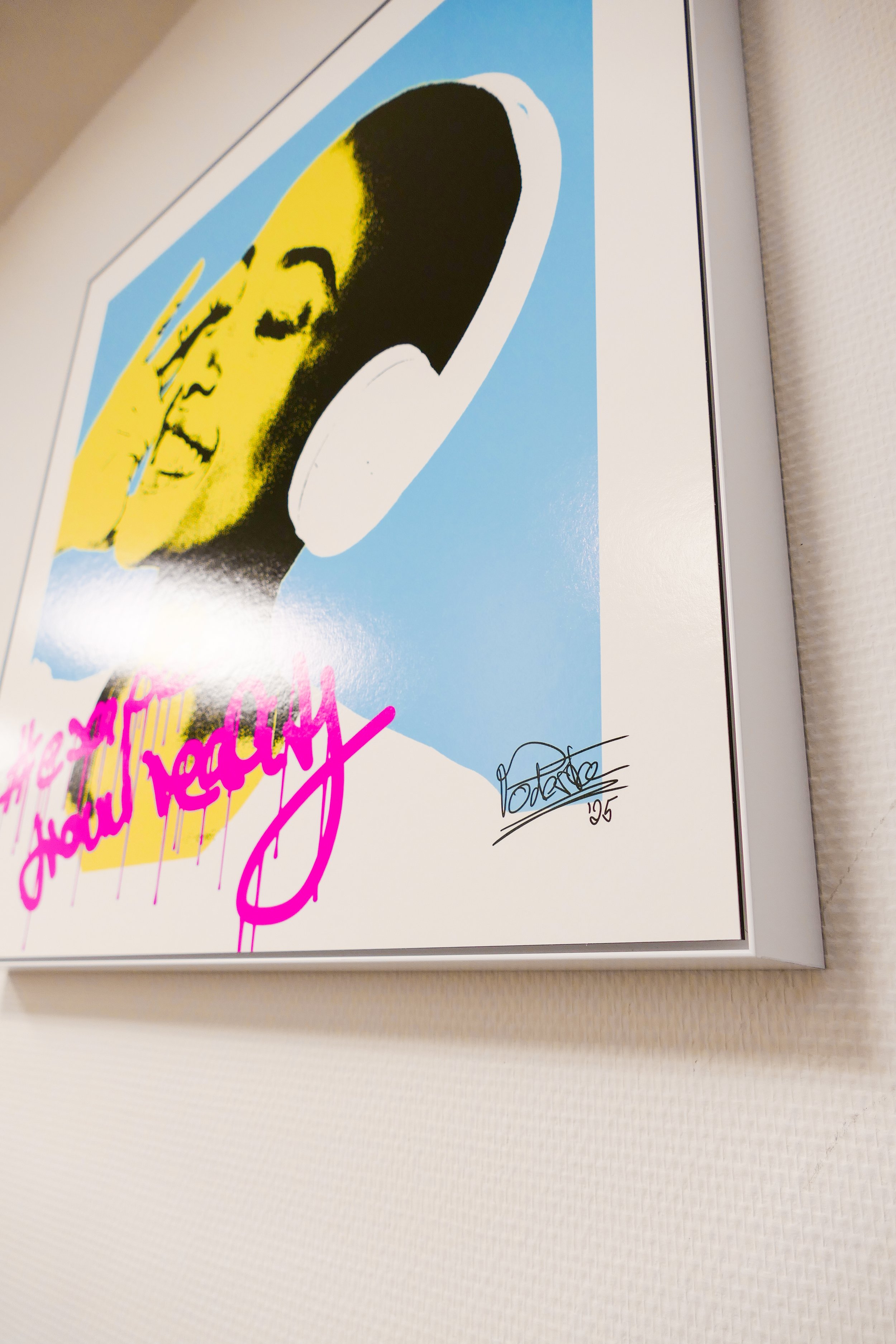 Kunstwerk mit einer stilisierten, gelben und schwarzen Porträtaufnahme eines lachenden Menschen, mit pinkfarbener Aufschrift '#escape from reality', und einer Unterschrift mit Datum 25.