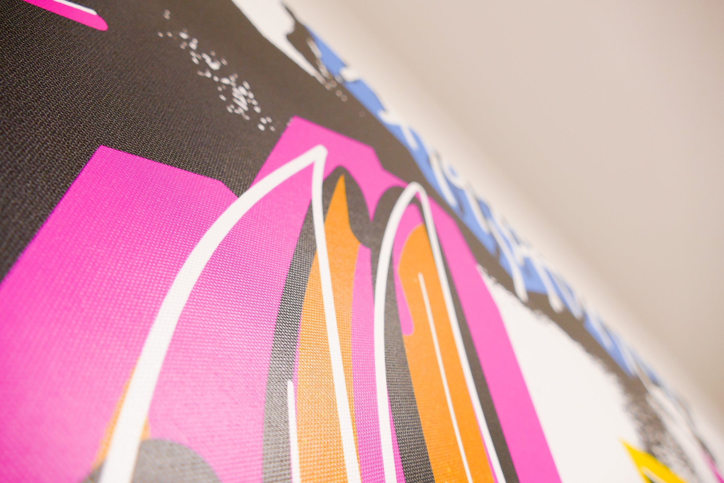 Nahaufnahme eines bunten Drucks mit pink, orange, schwarz, grau, und blauen Linien auf Stoff.