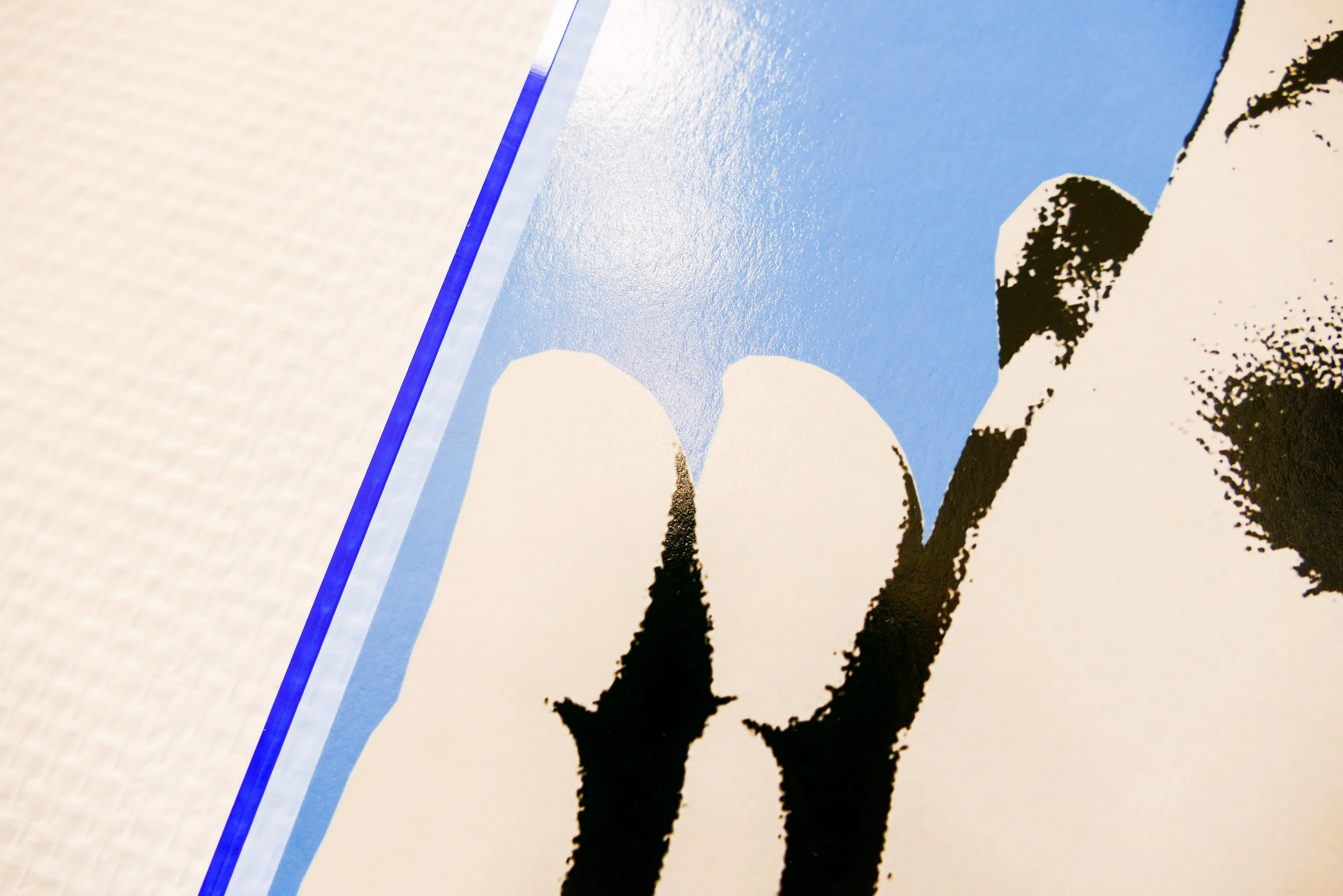 Nahaufnahme eines Farbdrucks mit Blau, Schwarz und Weiß, Darstellung einer menschlichen Figur mit Fokus auf Beine und kurze Kleidung.