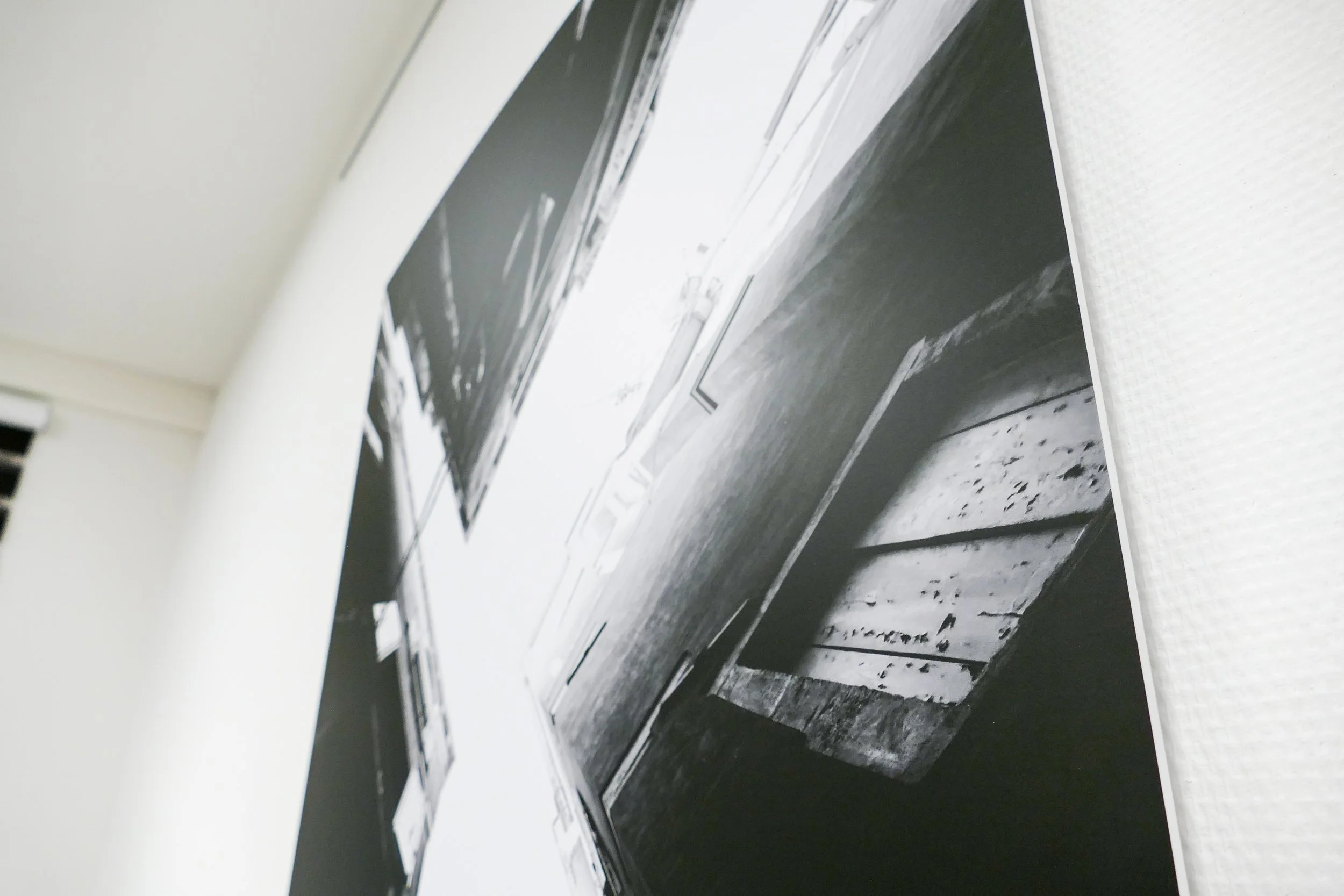 Schwarz-Weiß-Fotografien an der Wand, die alte Holzbohlen und eine Kiste zeigen.
