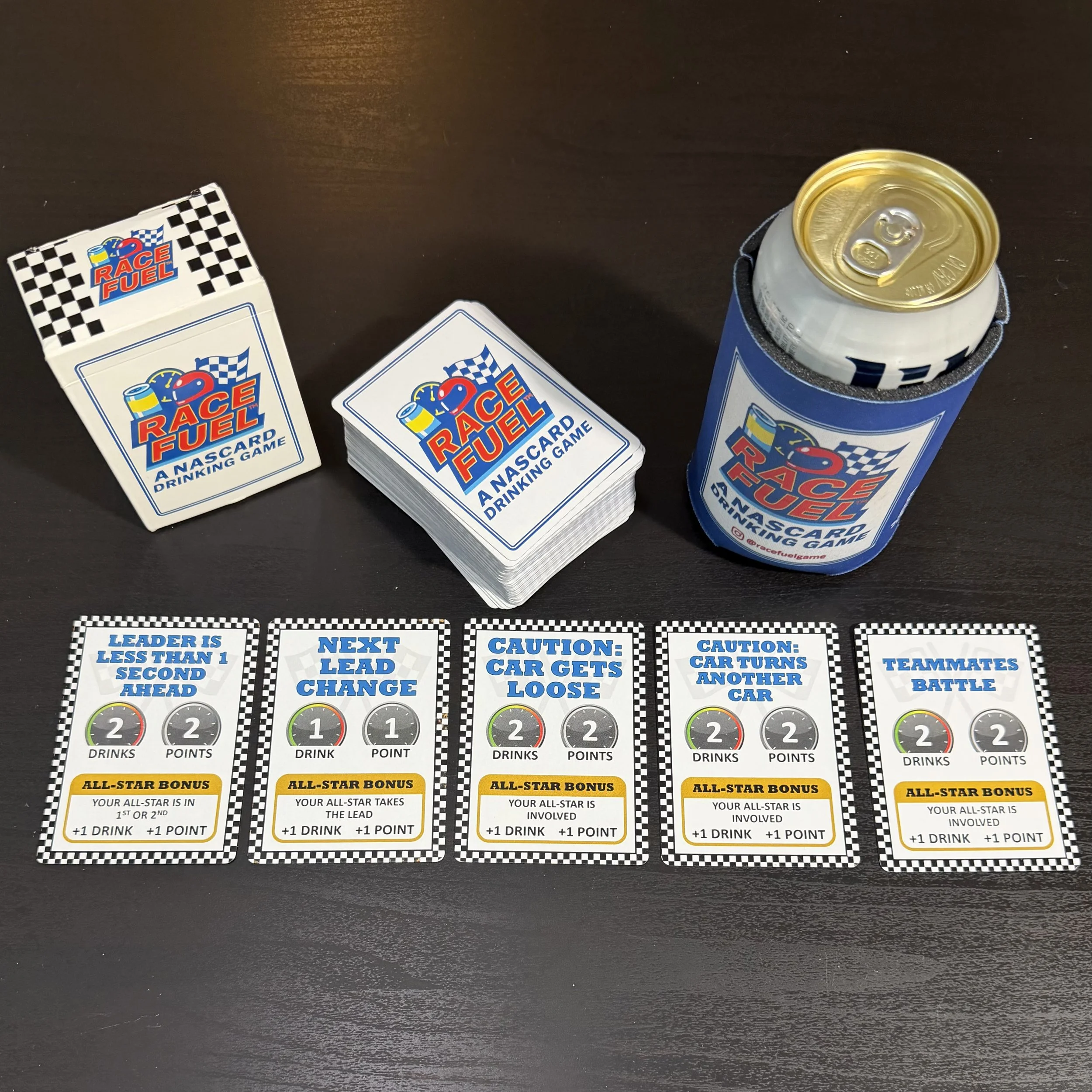 Race Fuel racing card game setup with event cards, All-Star bonus cards, game box, deck, and can sleeve for live race gameplay.