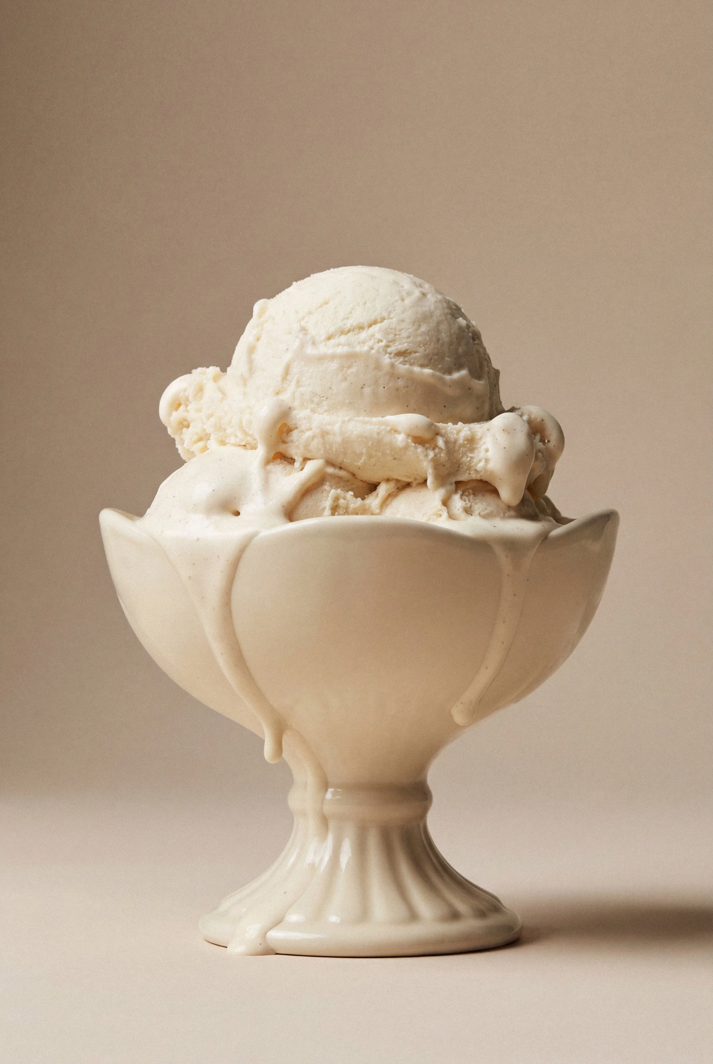 A bowl filled with vanilla ice cream topped with a scoop of vanilla ice cream, served in a white, decorative bowl.