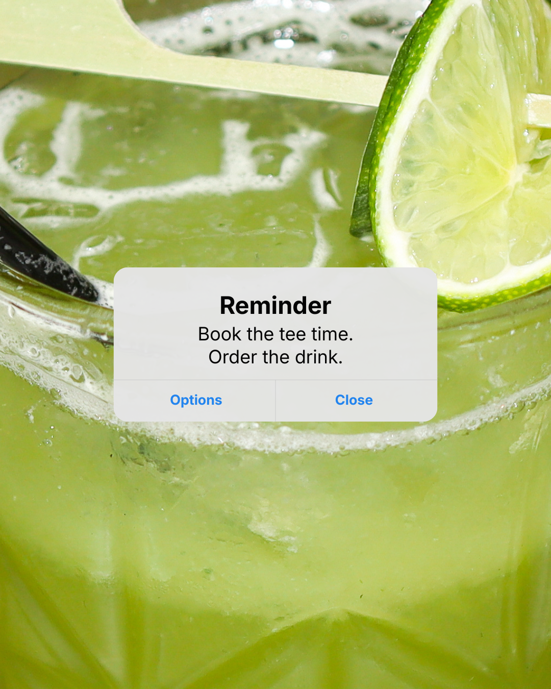 Close-up of a lime wedge and a glass of lime-infused beverage with bubbles. A reminder message overlay instructs to book a tee time and order the drink.