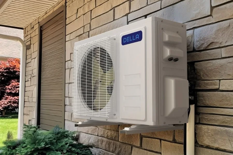 An outdoor air conditioning unit mounted on a brick wall of a house.