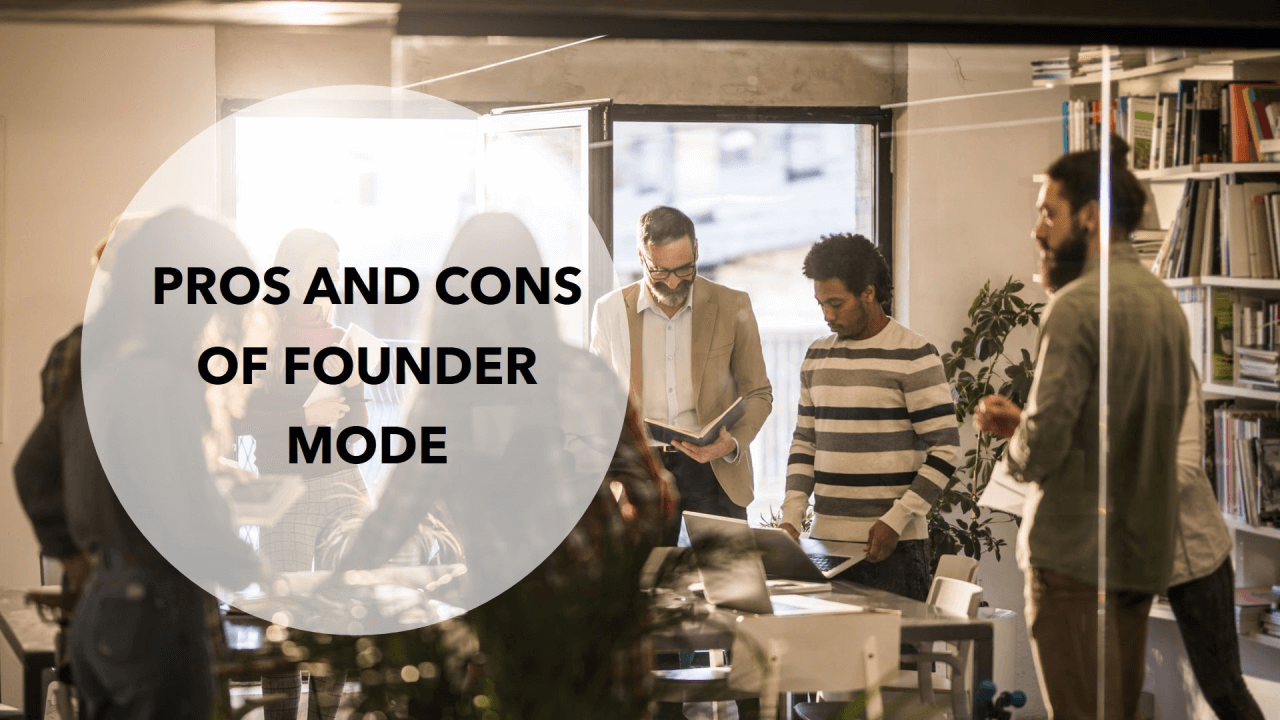 Group of people in a meeting or discussion in a modern office with bookshelves, some standing around a table, and a large window letting in natural light.