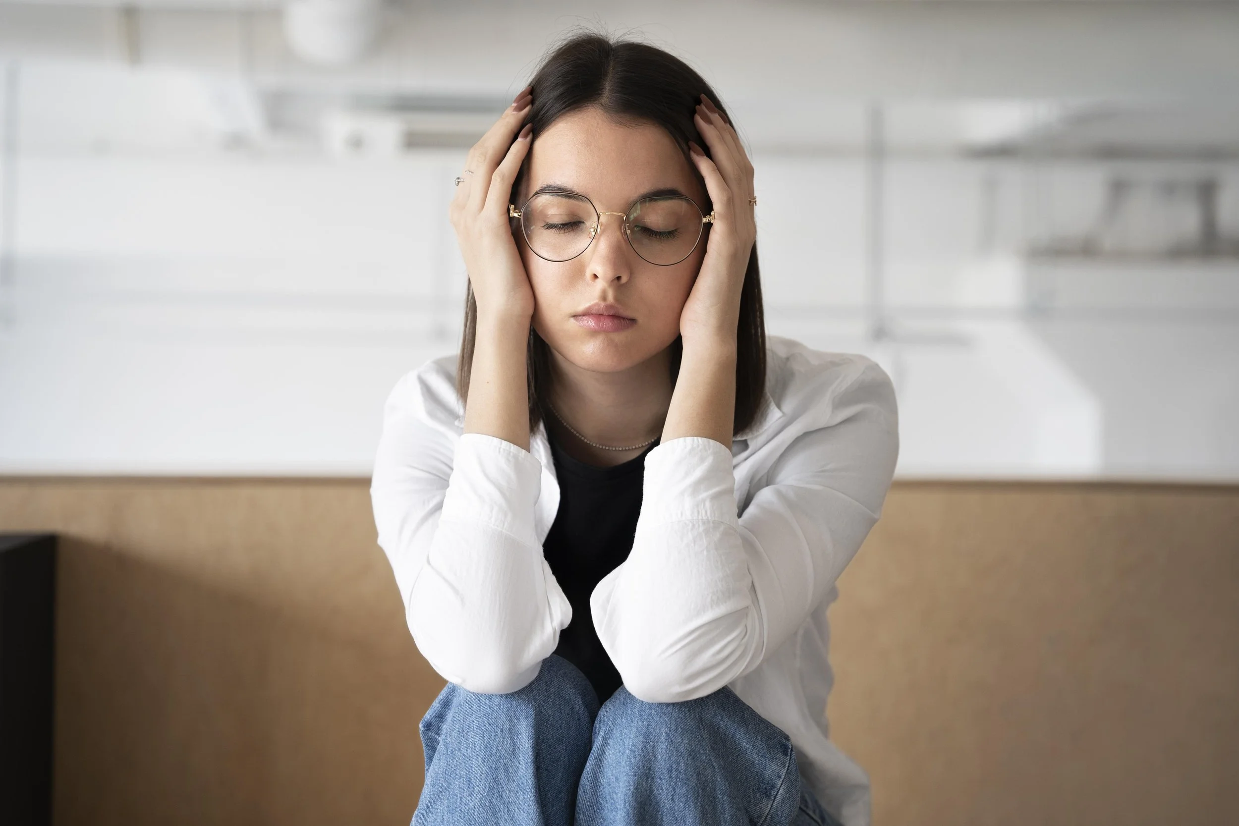 A woman experiencing stress and burnout while holding her head - Integrative Healthcare Alliance