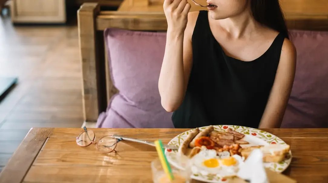A woman eating her breakfast at a restaurant - Integrative Healthcare Alliance