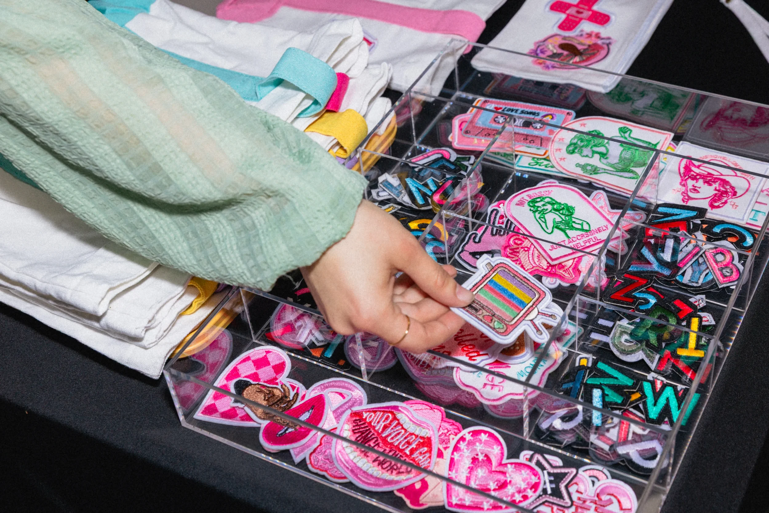 Guest selecting an embroidered patch from a live patch bar display case at an event