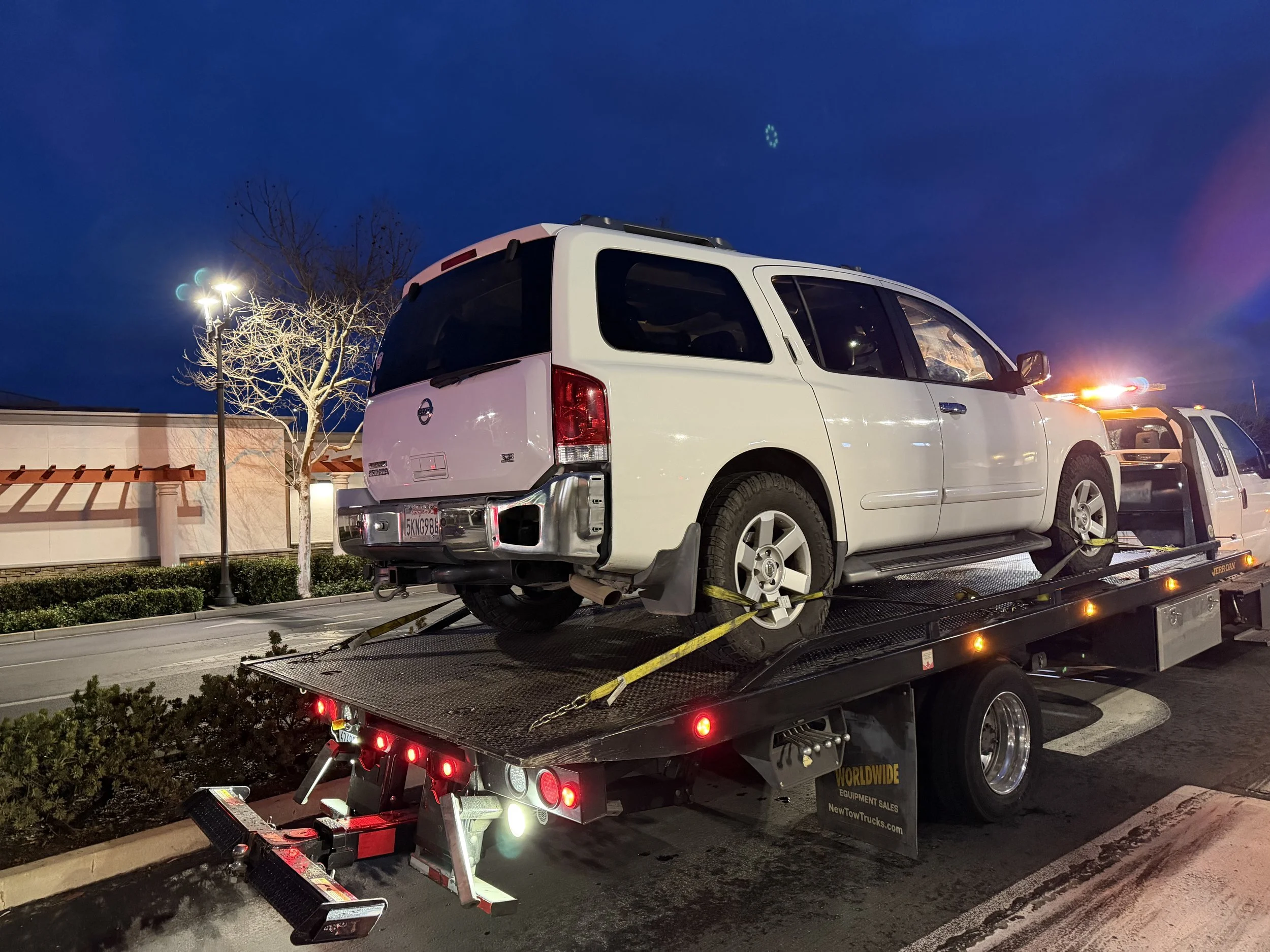 Flatbed towing service in Antioch CA transporting a Nissan Armada SUV at night by 24-7 Rescue Towing.