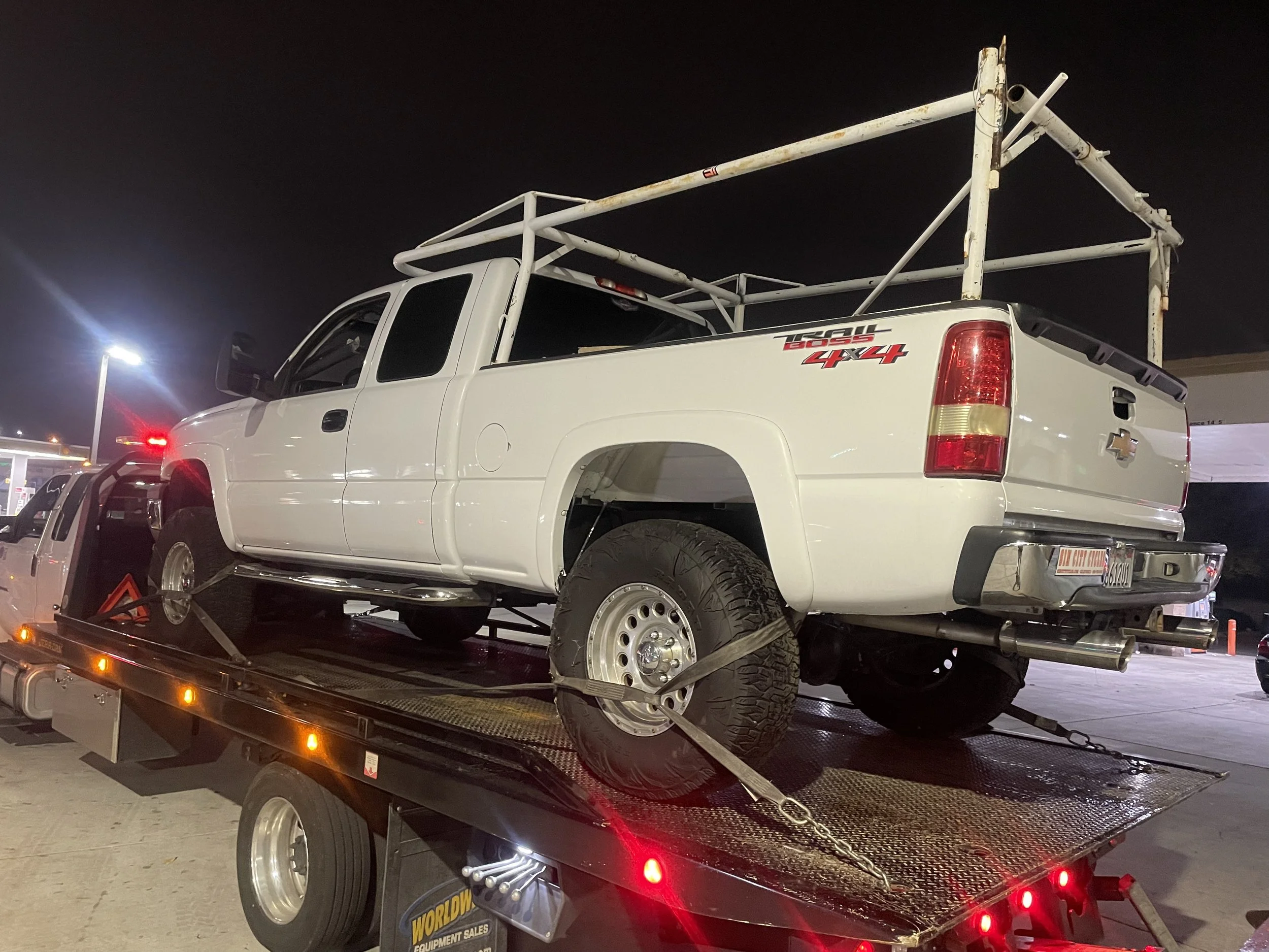 24-7 Rescue Towing hauling a Chevy 2500HD work truck on a flatbed tow truck in Discovery Bay, CA at night