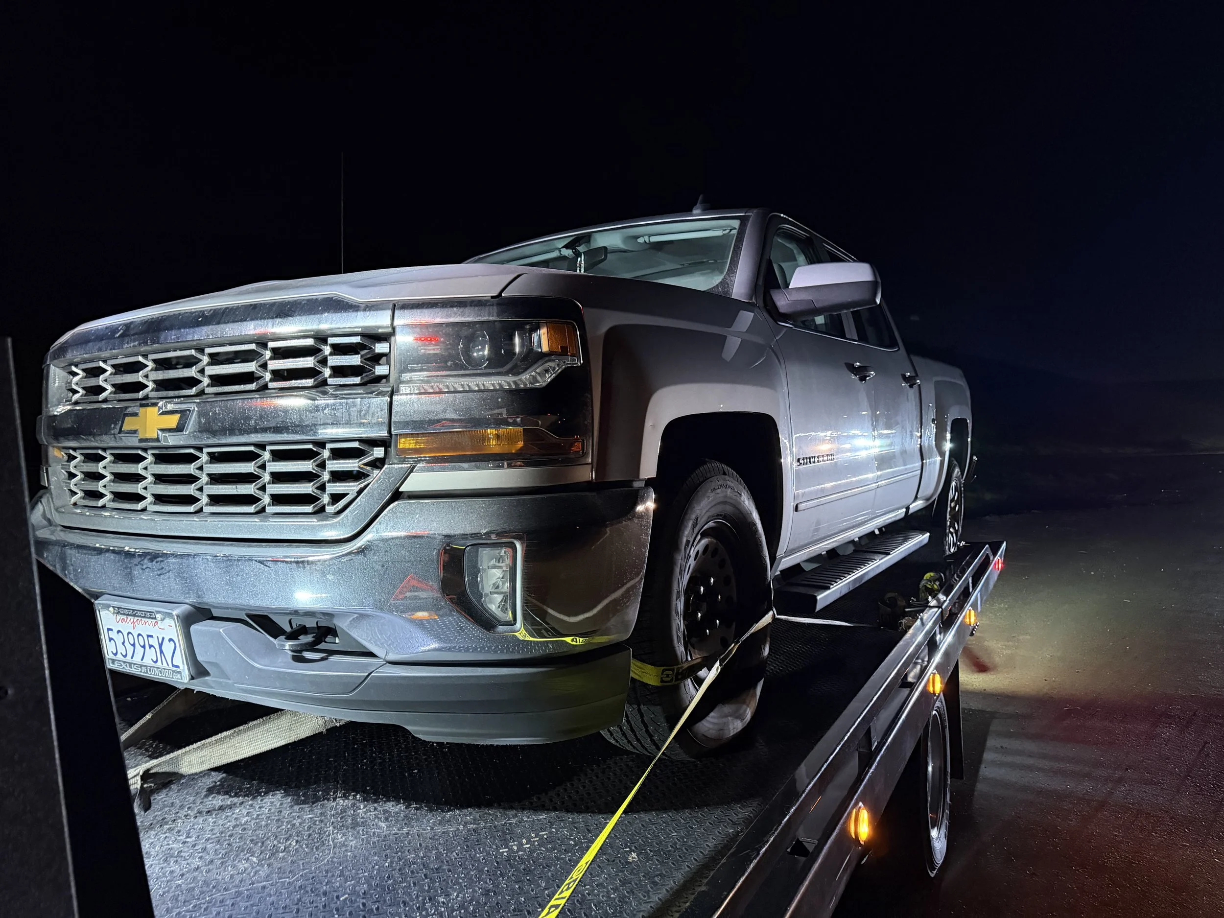24-7 Rescue Towing transporting a Chevrolet Silverado on a flatbed tow truck at night near Discovery Bay, California