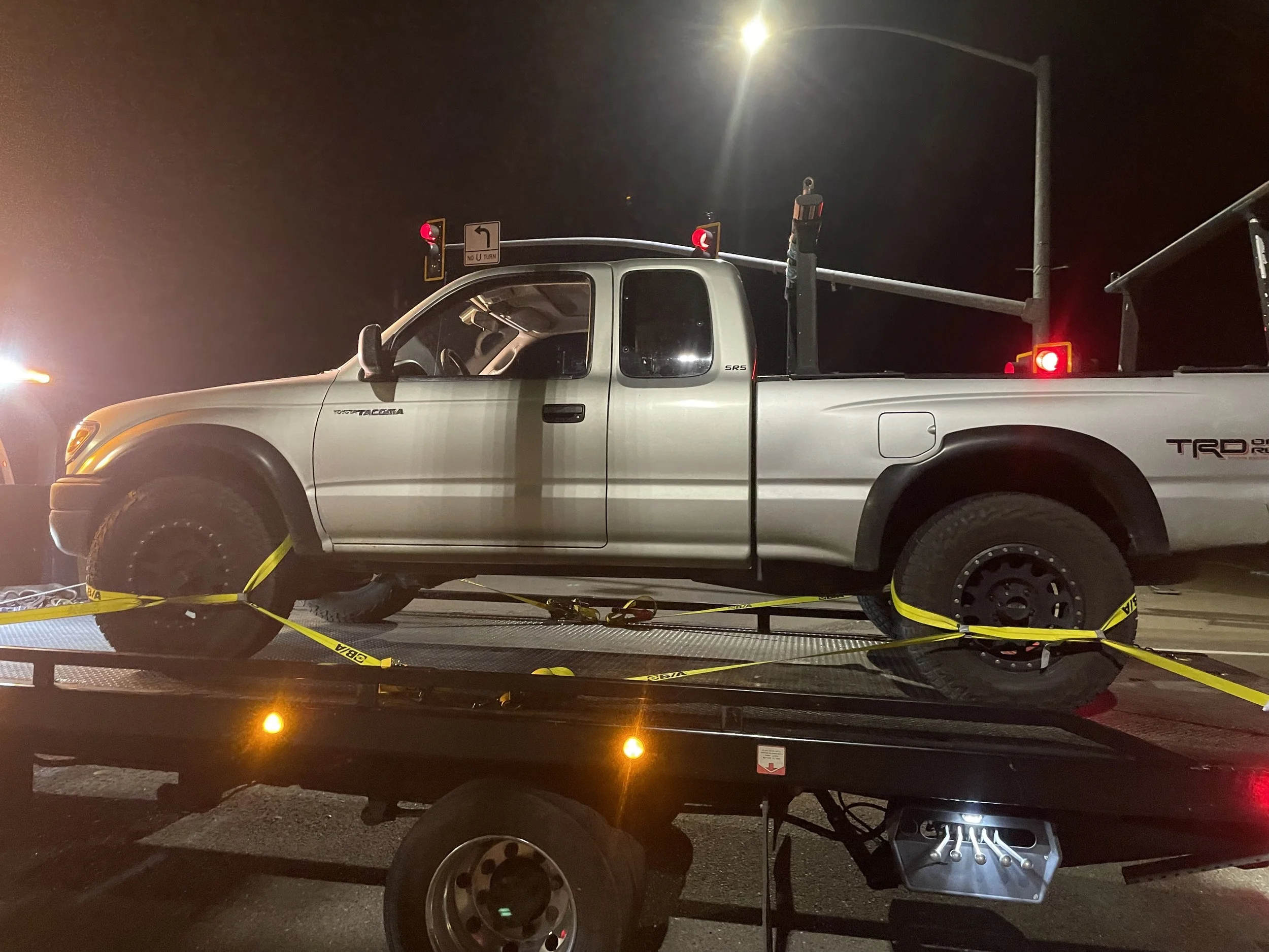 24-7 Rescue Towing towing a Toyota Tacoma pickup truck at night in Discovery Bay CA using a flatbed tow truck