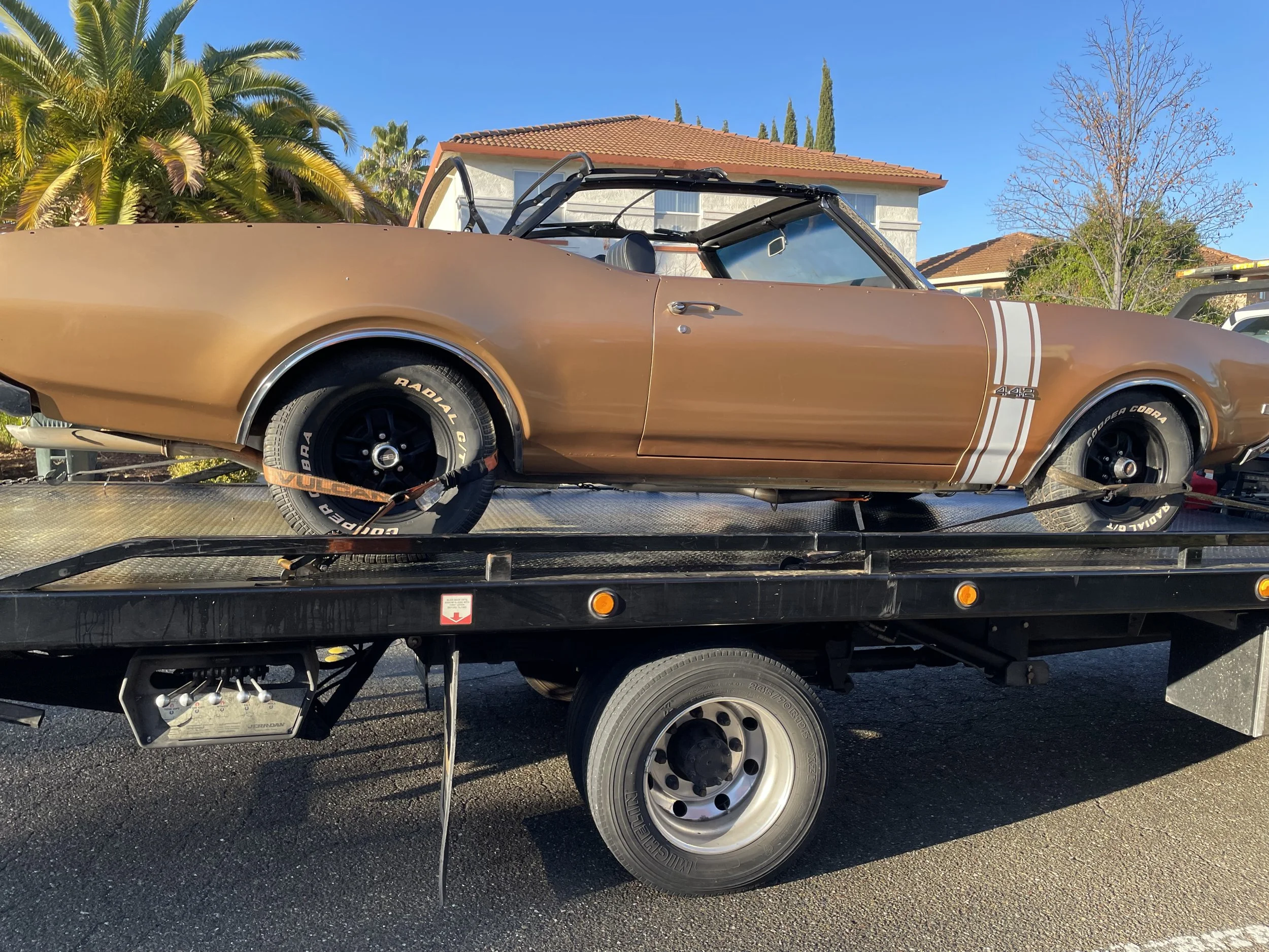 24-7 Rescue Towing transporting a classic convertible muscle car on a flatbed tow truck in Discovery Bay CA