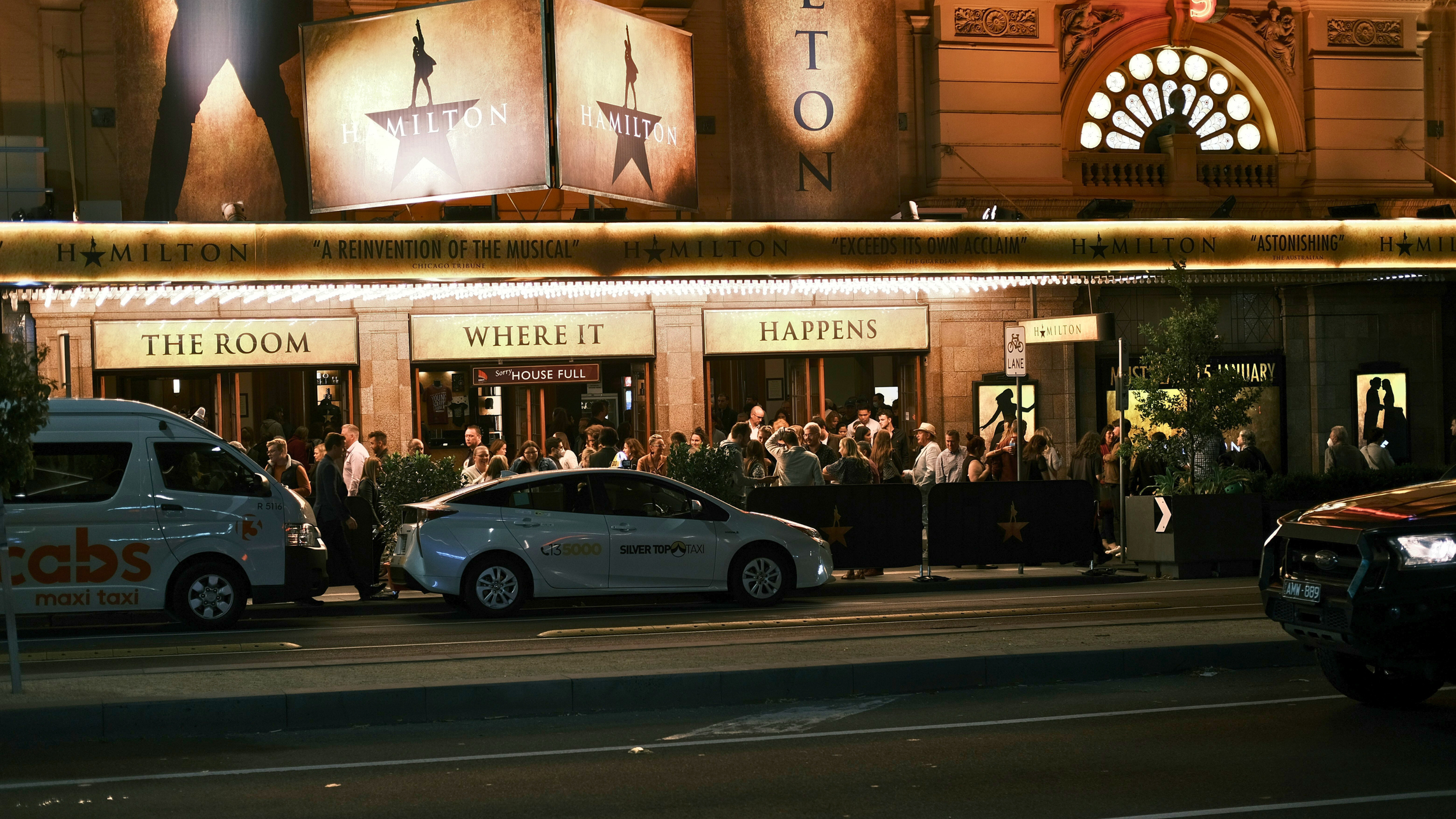 Exterior view of the theatre with Hamilton imagery including a sign that says "The Room Where it Happens" and the sillouette of a person with a gun shooting into the air.