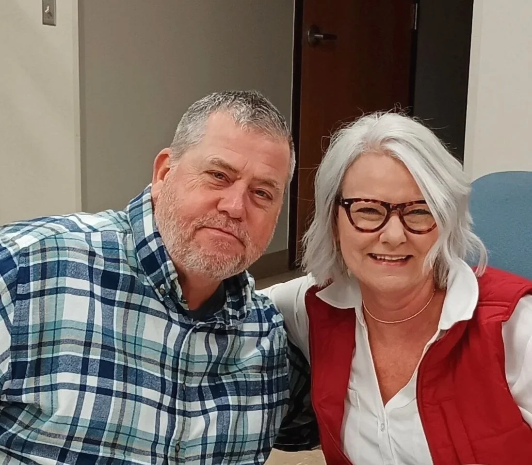 Robby Parrish and his wife smiling and sitting close together in an indoor setting.
