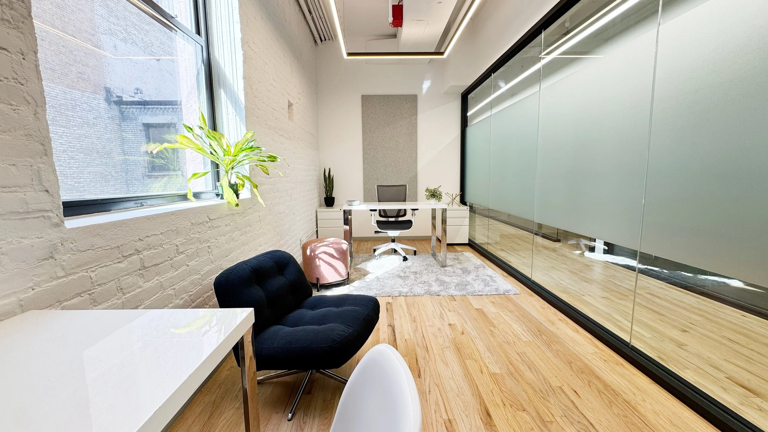 Spacious furnished private office with hardwood floors and large windows
