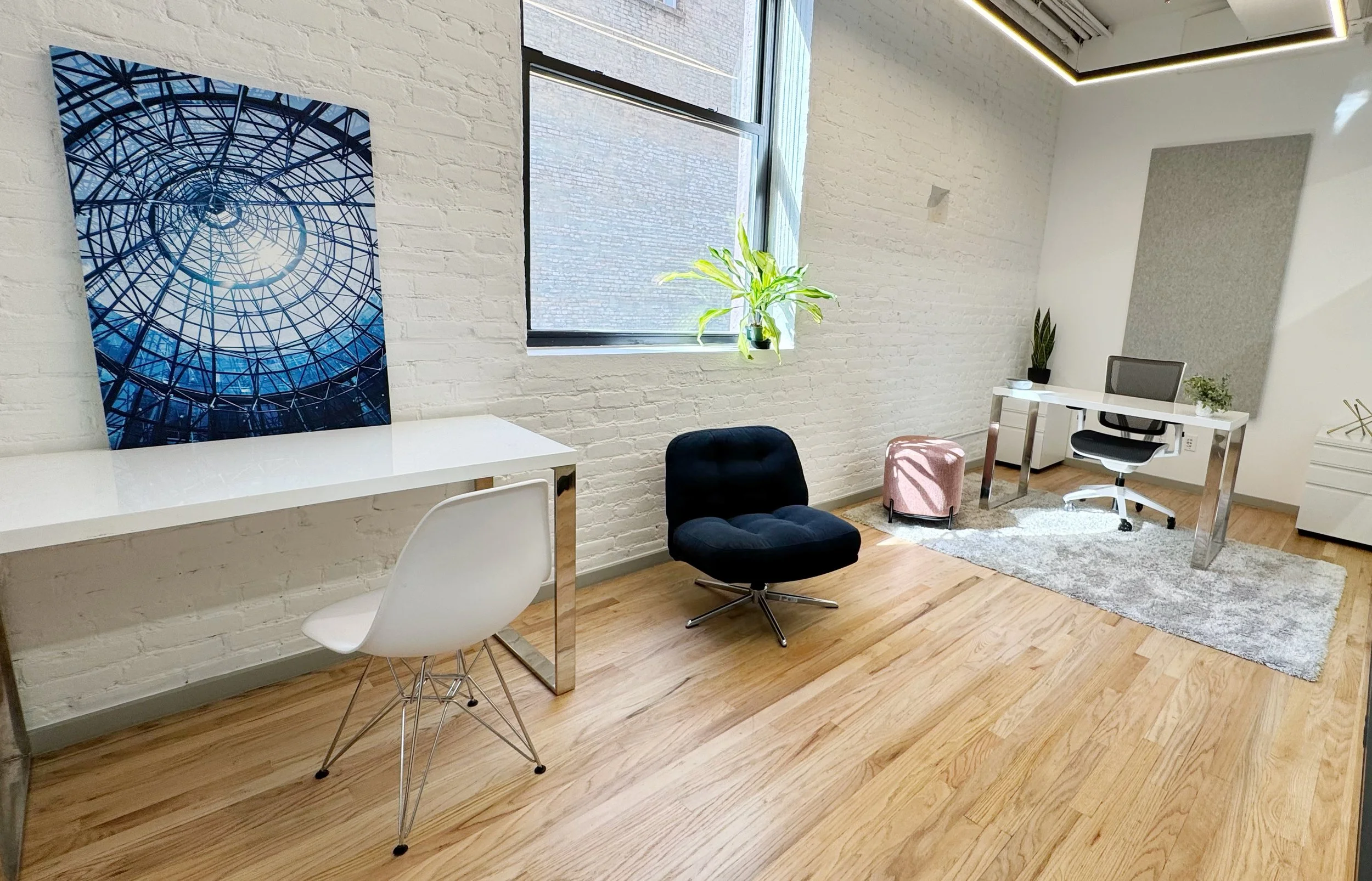 Furnished private office suite with desk, chair, and natural light