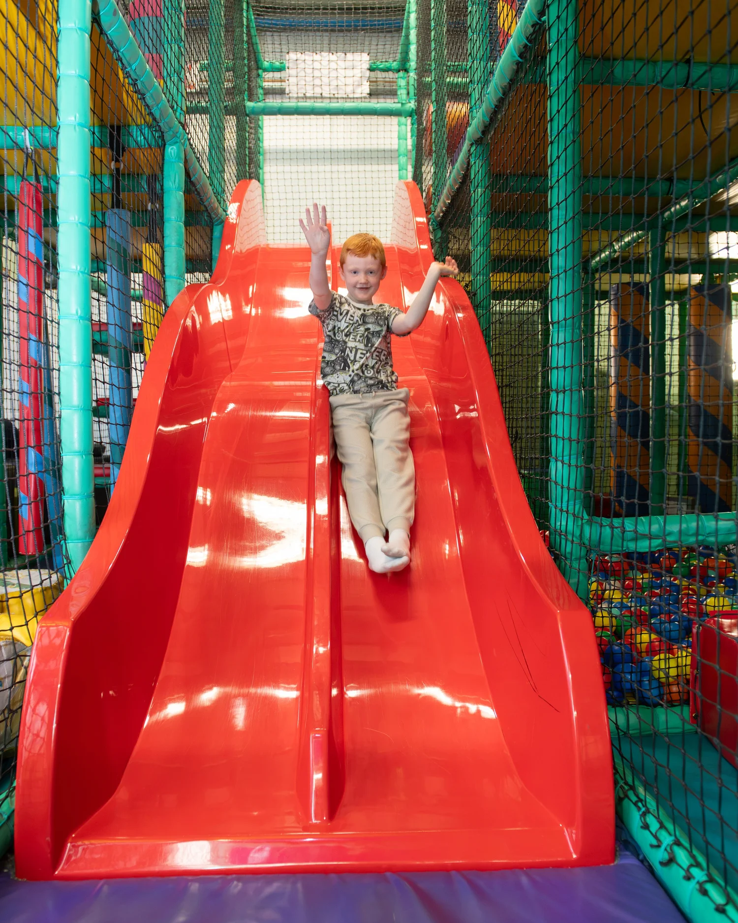 Child smiling on the big red slides at Diddy Middy's soft play centre in Cleckheaton