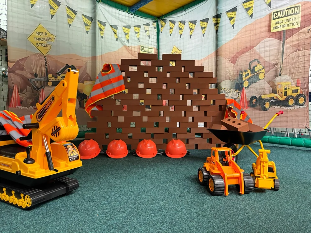 Construction themed imaginative play area with toy diggers and building bricks at Diddy Middy's