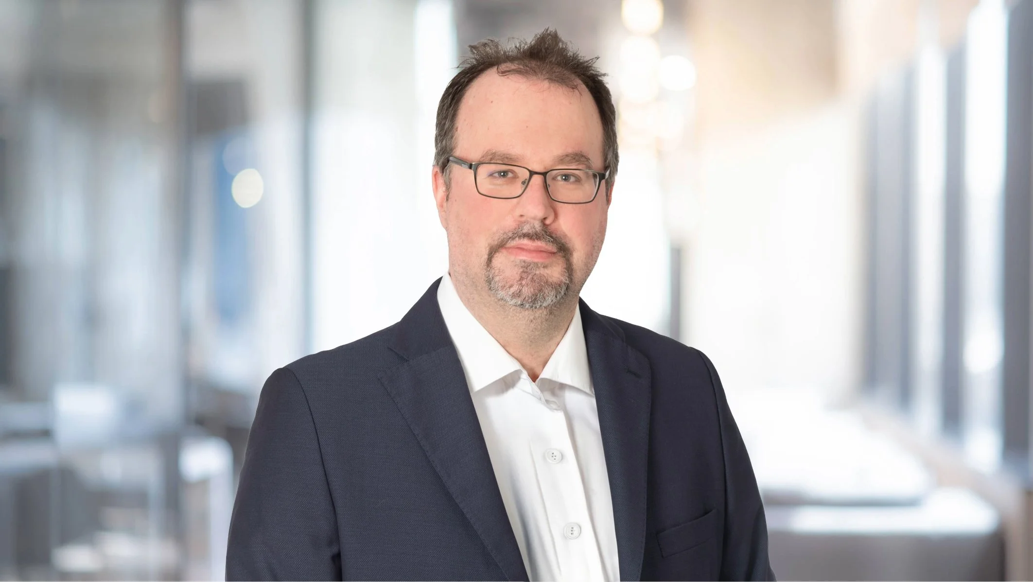 Geschäftsmann trägt Anzug und Brille, im Büro.