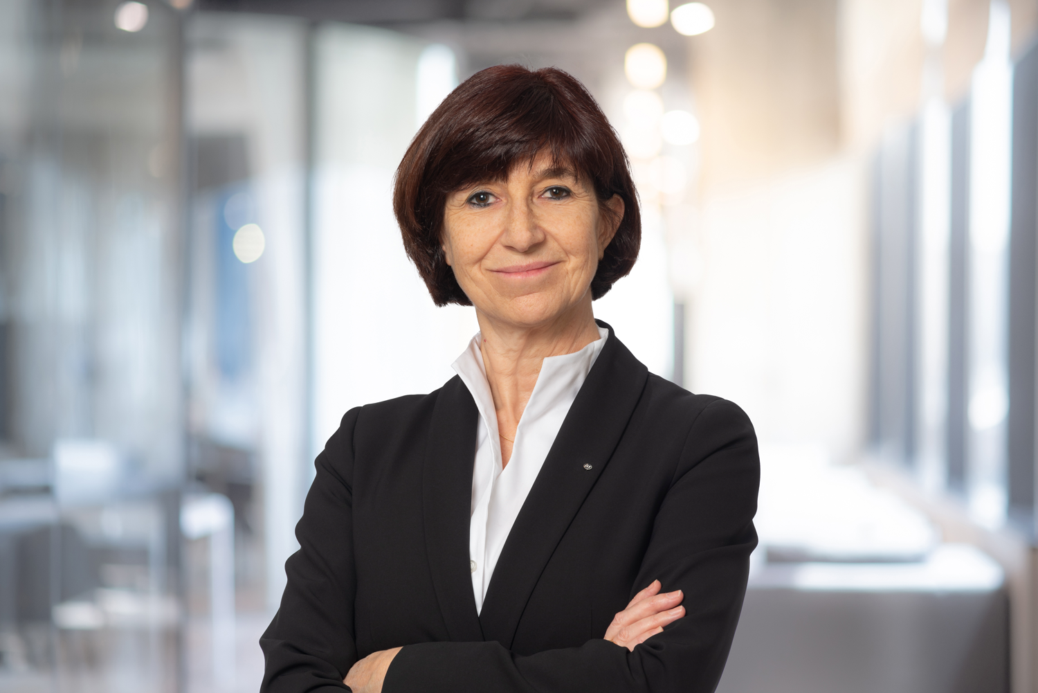 Selbstbewusste Frau in formeller Kleidung mit crossed arms in modernem Büro