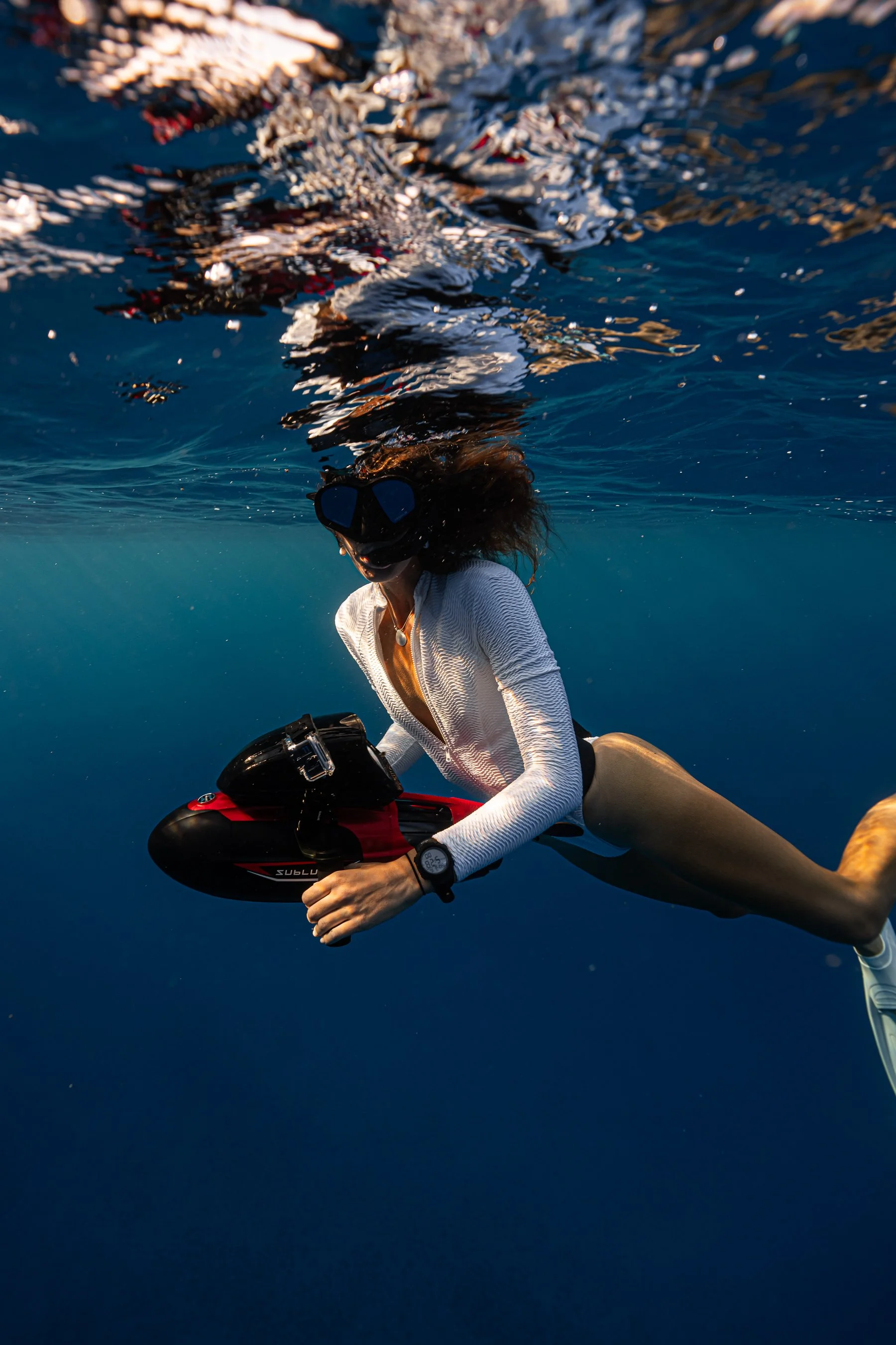 Woman with a snorkel mask in underwater while holding a Sublue vapor flagship model red color