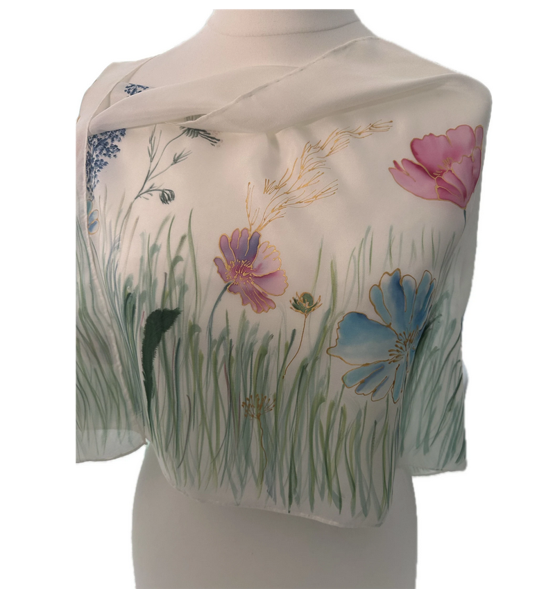 A white shawl with colorful floral and grass patterns draped over a mannequin torso