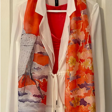 Colorful kimono with floral and cloud patterns hanging on a door.