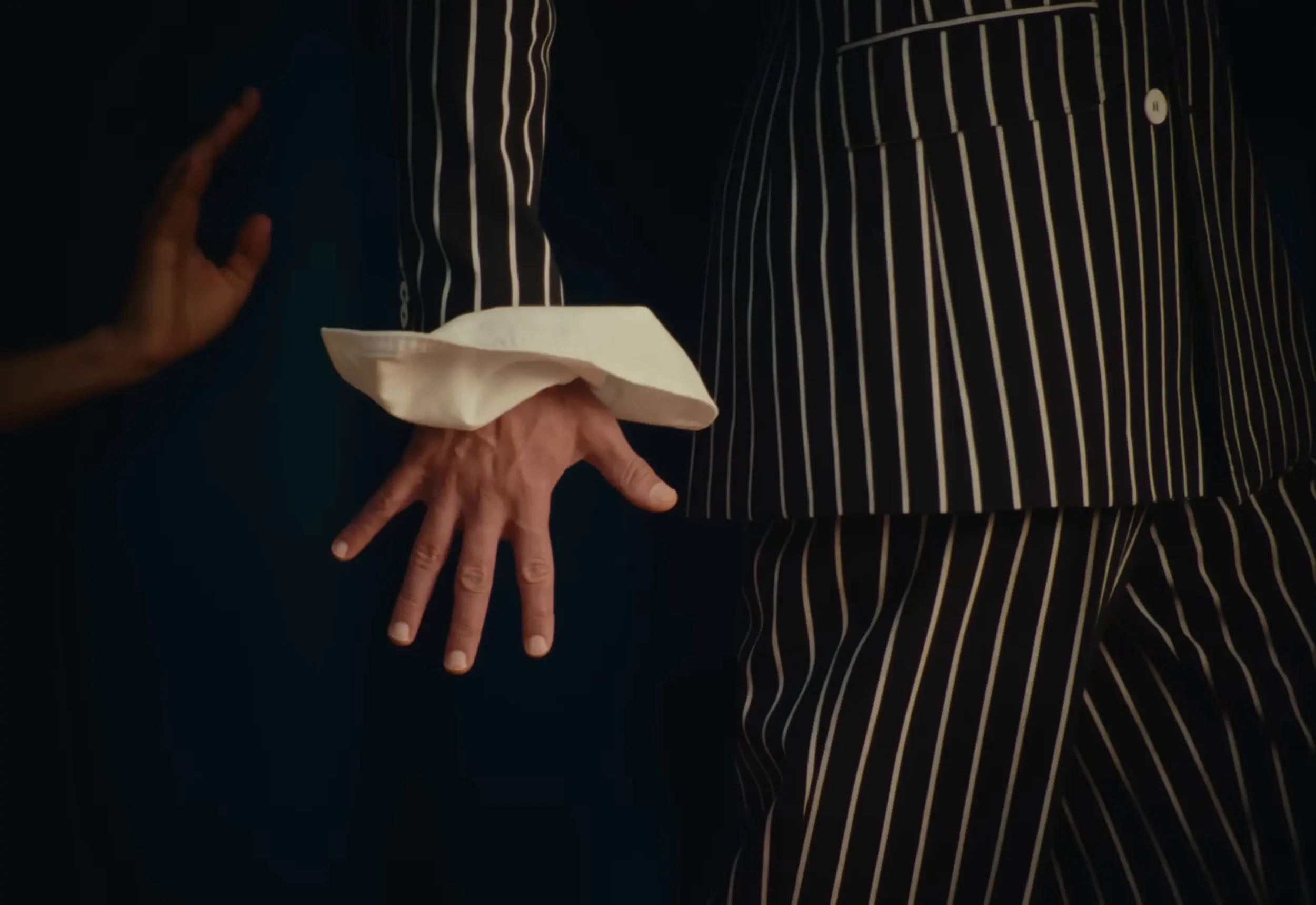 Detailaufnahme Herrenmode: Hemdmanschette und Hand an dunklem Nadelstreifen-Anzug – Filmstill Fashionfilm Mastlicht Media