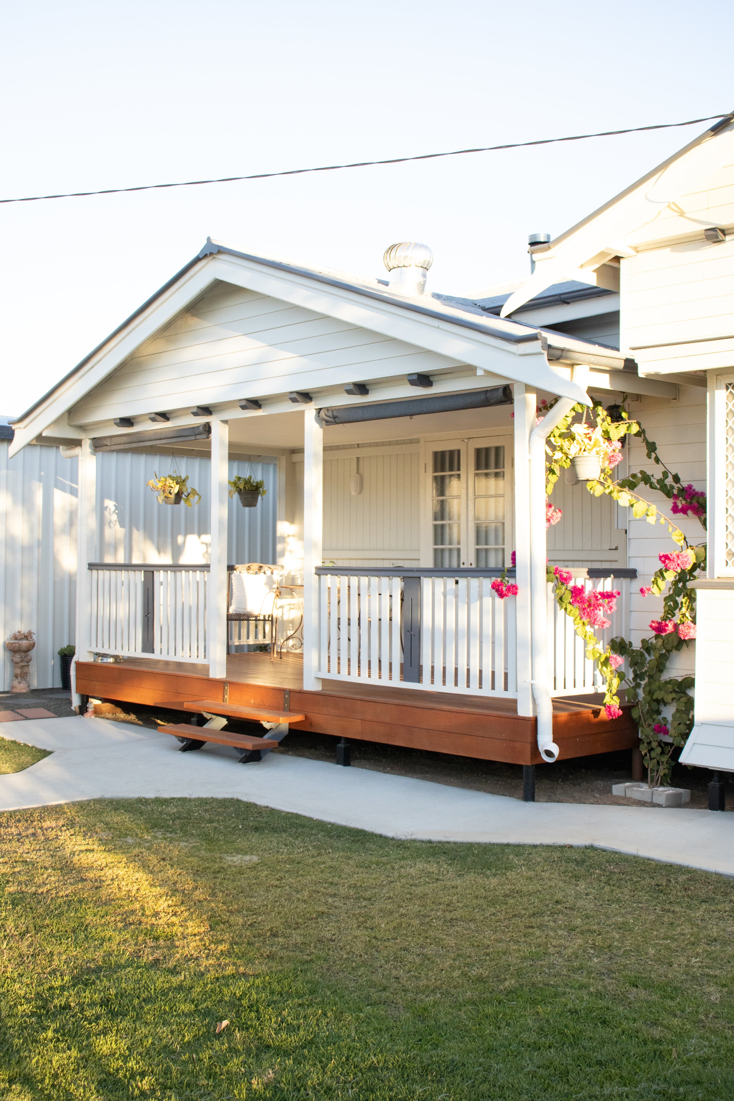 A front verandah on a Queenslander style home with a concrete footpath suounding.