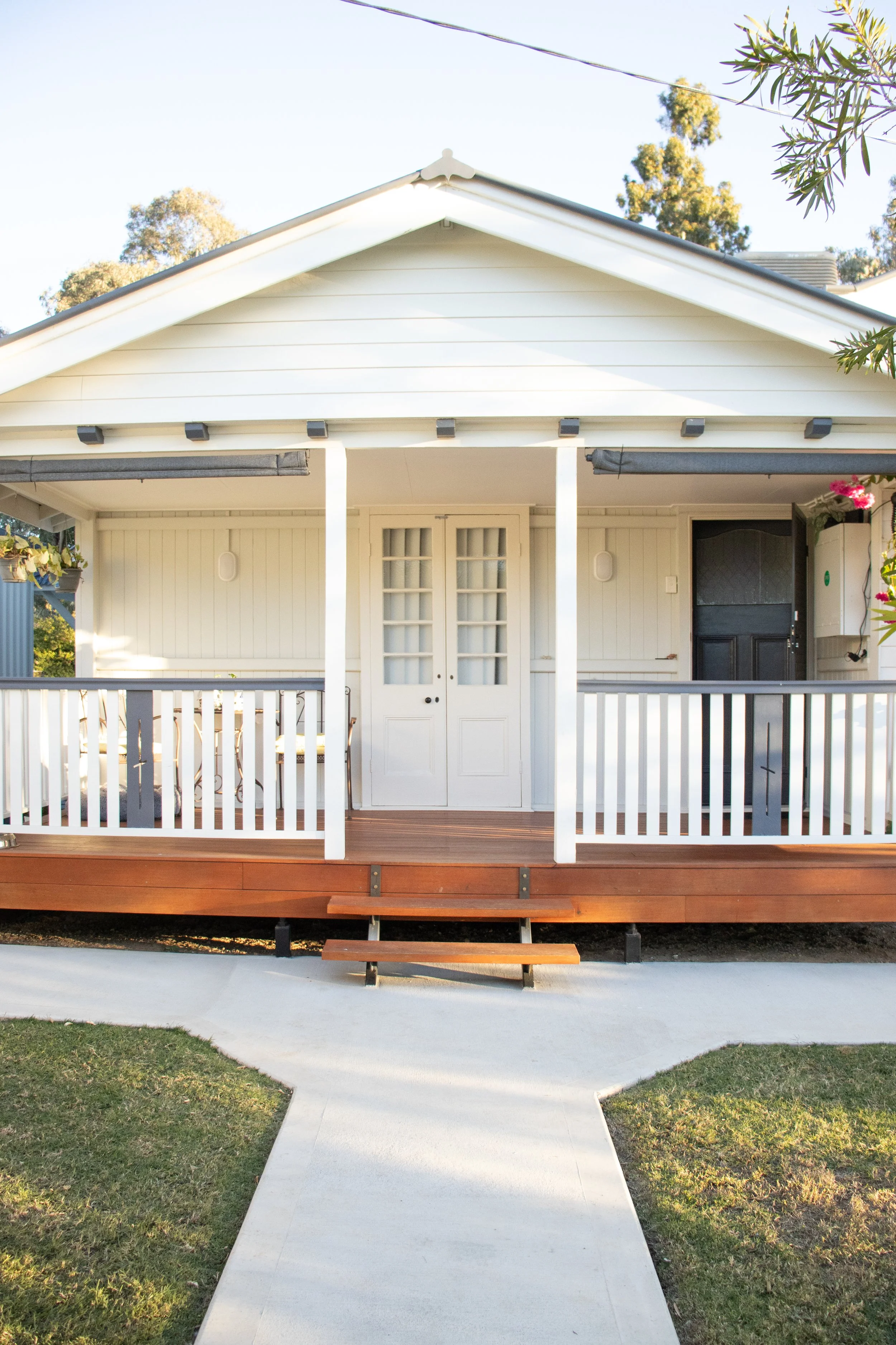 A front verandah on a Queenslander style home with merbau timber steps and white hand railings.
