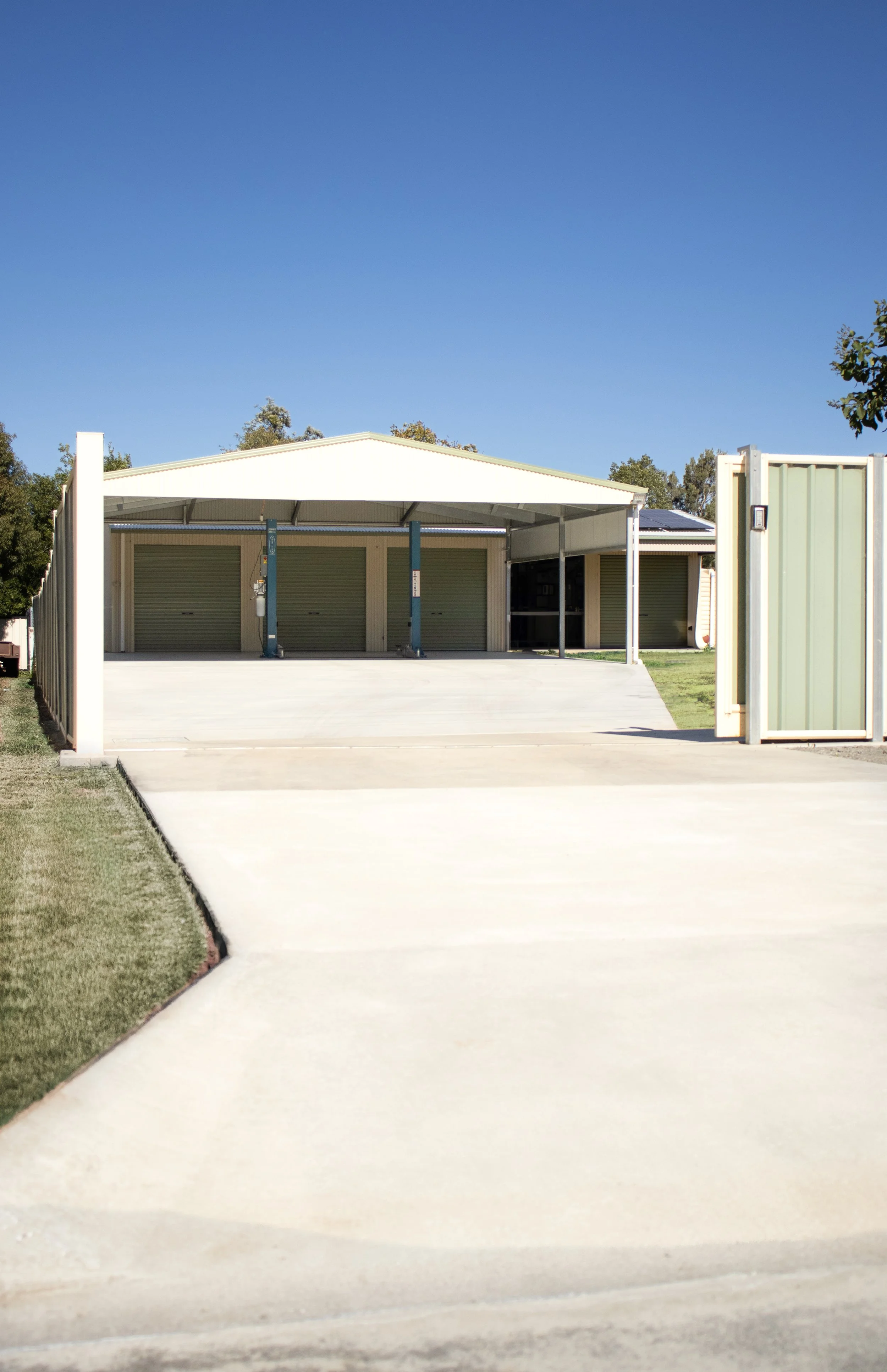A three bay shed with extension and concrete driveway extending past electric gate to street.