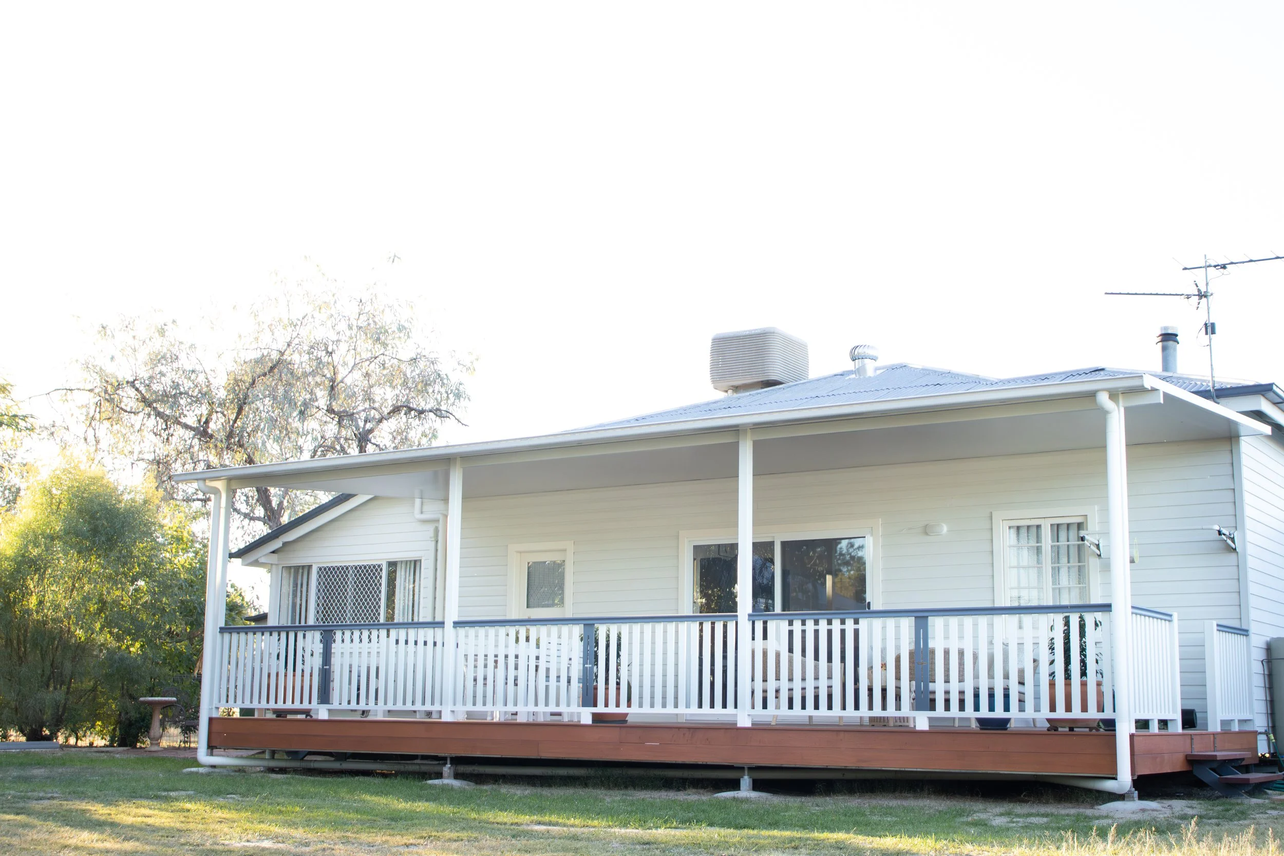 A rear deck with merbau timber and solarspan roof, with white handrailings.