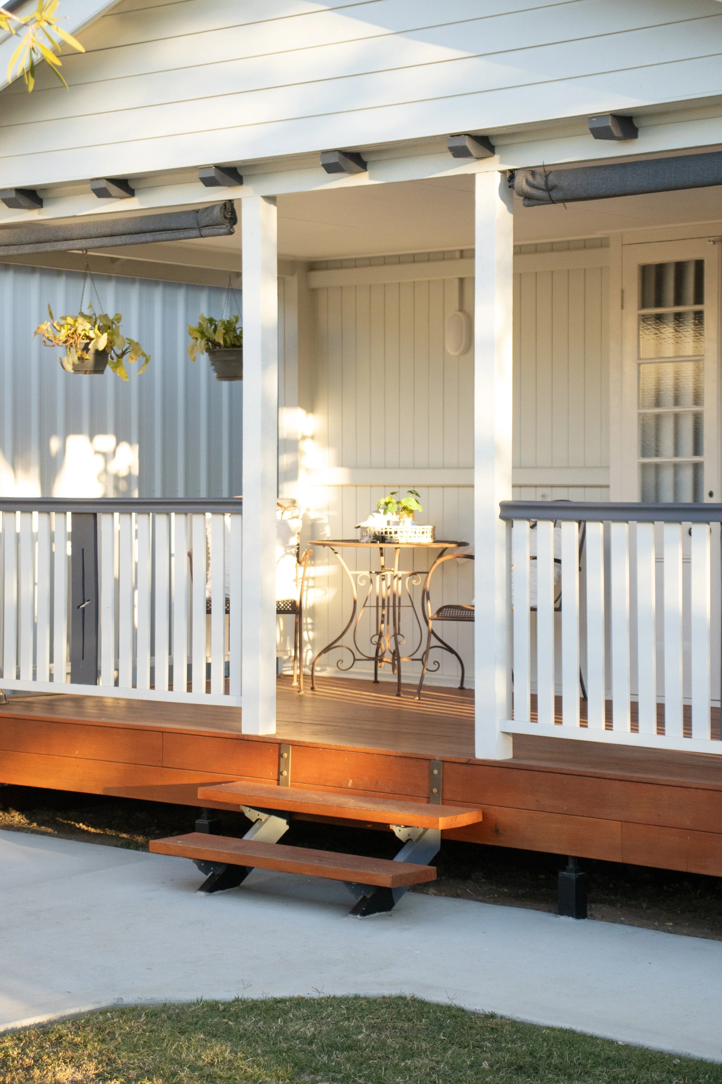 A front verandah on a Queenslander style home with merbau timber steps and white posts.