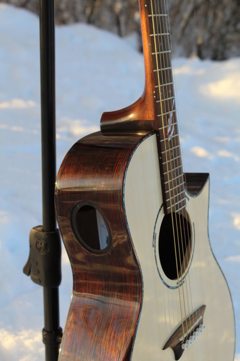 Side view of the Snowbird guitar showing the arm bevel, side soundport, and contrasting wood grains.