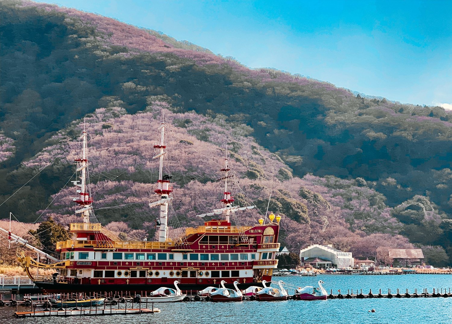 Pirate ship on Lake Ashi below cherry blossom hillsides in Hakone