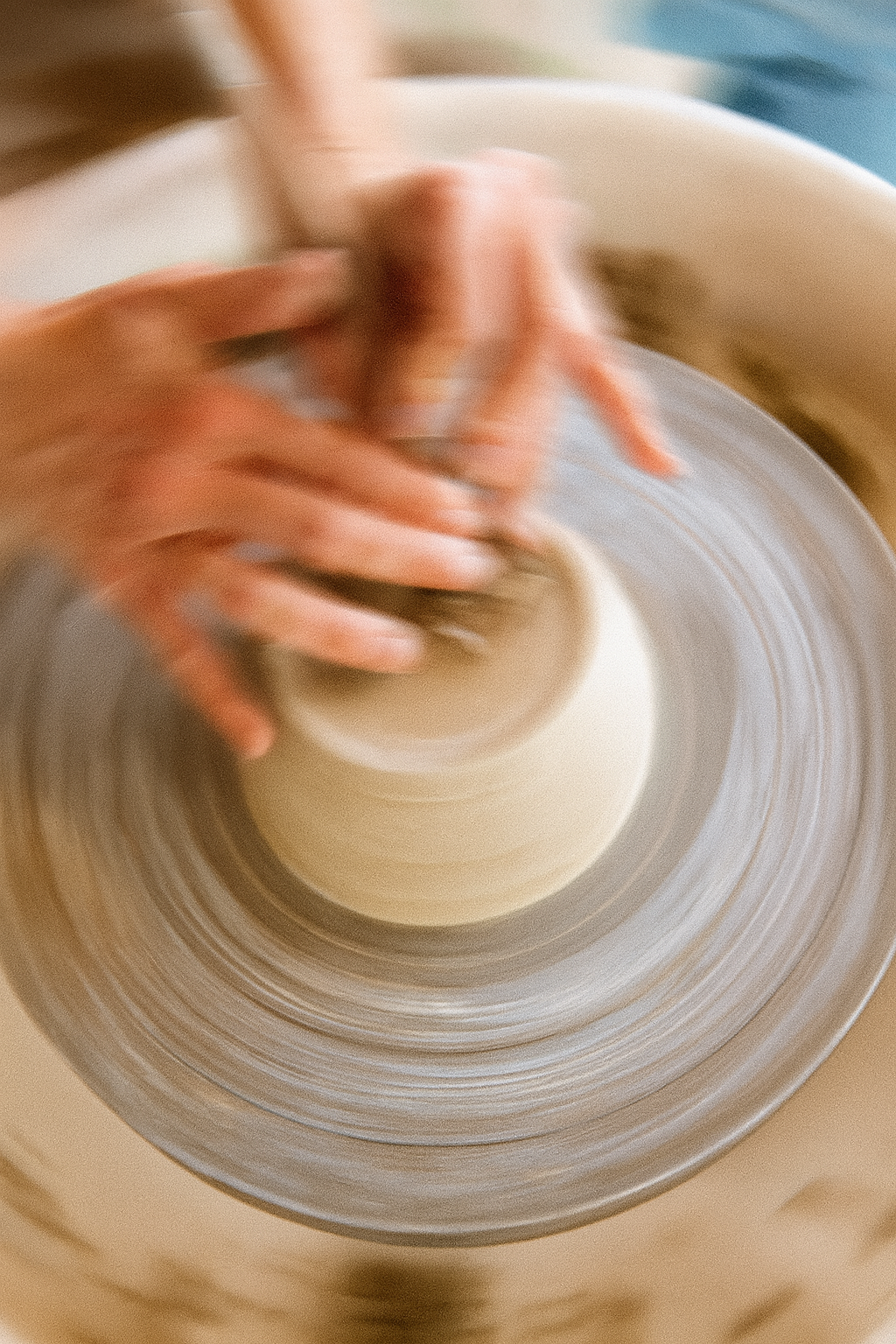 Mains d’une céramiste façonnant une pièce en argile blanche sur un tour de potier, travail artisanal en atelier.
