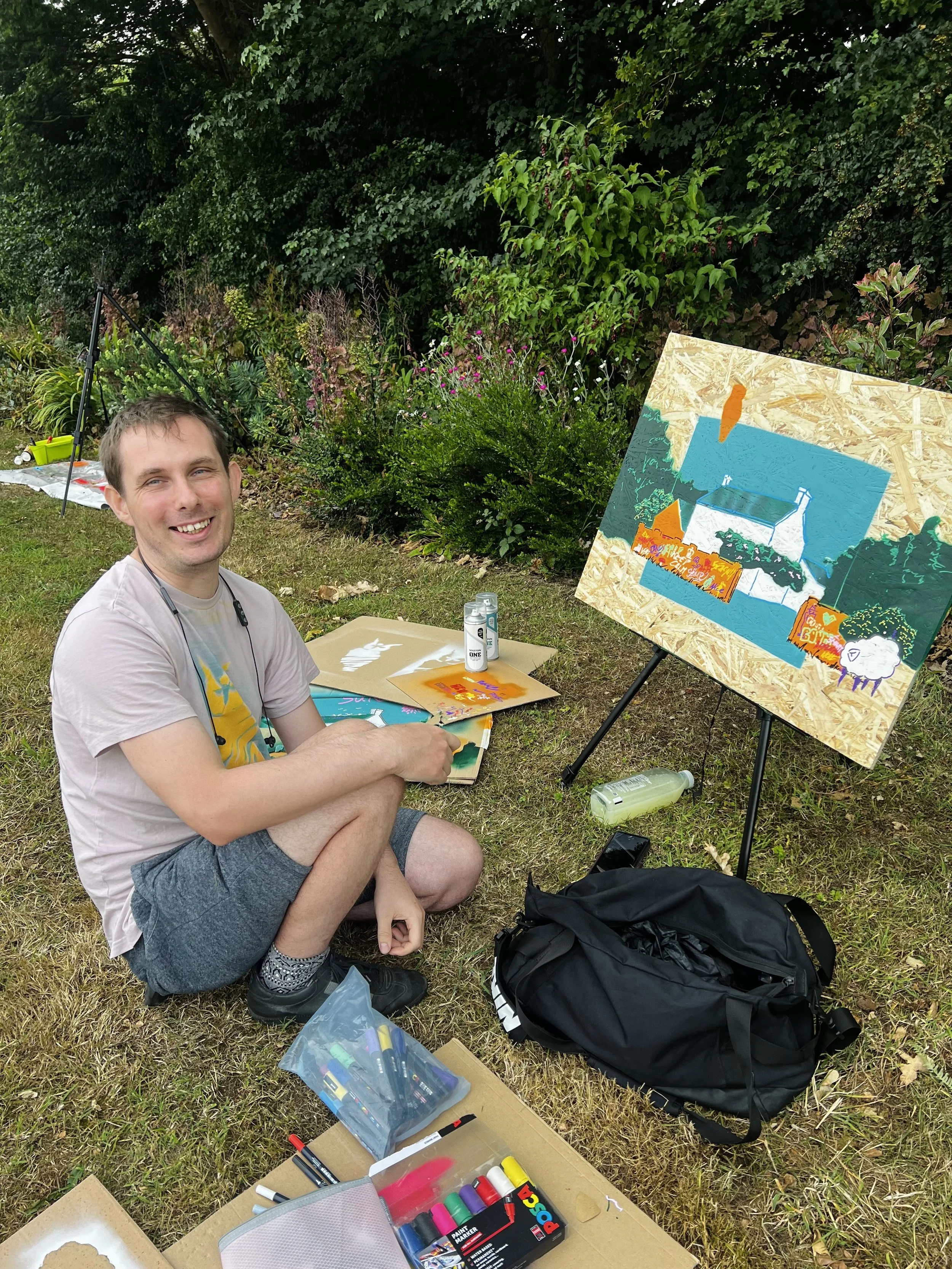 Artist painting, sat on the grass