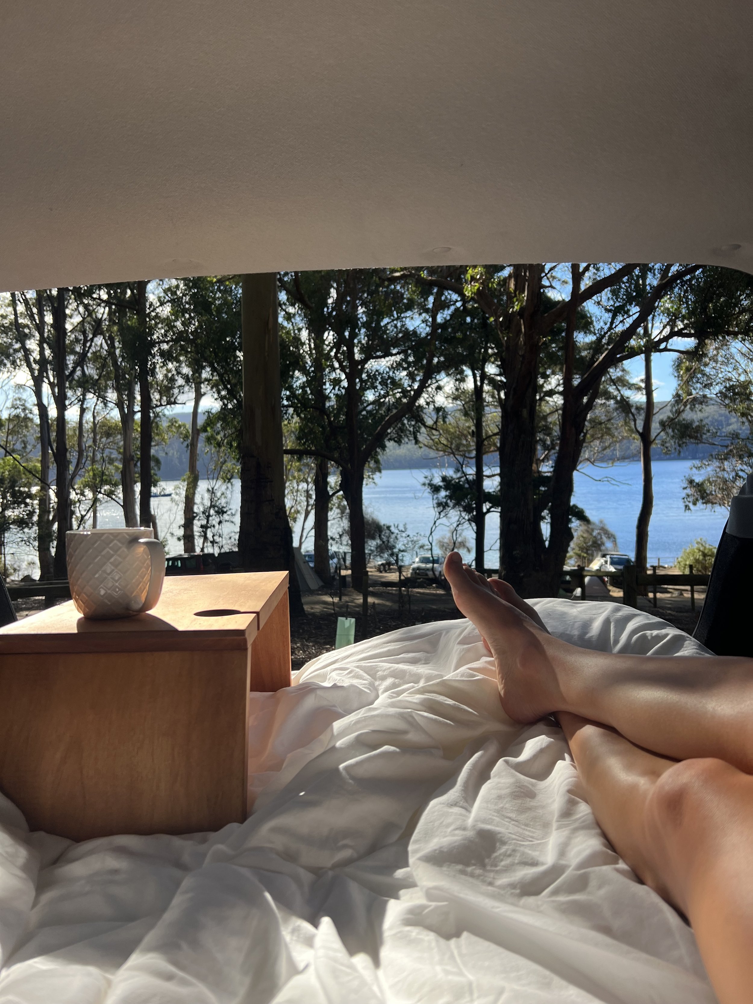 Solo camping in a Tasmanian National Park. Girls outside in the wild. Fortescue Bay on the Tasman Peninsula. A warm day with sunshine drinking a tea with a view.