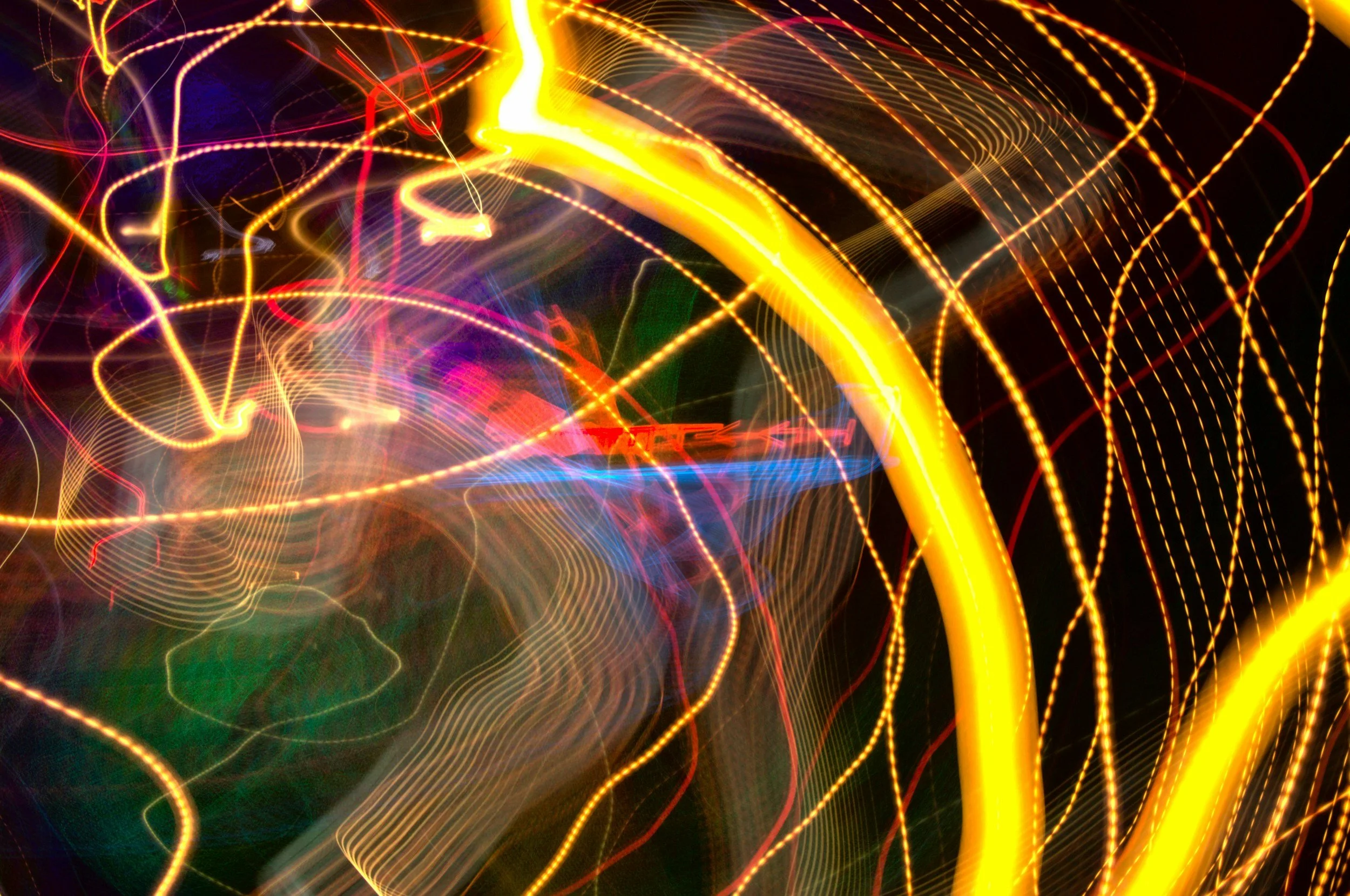 Abstract photo of colorful neon lights and streaks of light in motion, creating a vibrant and dynamic pattern against a dark background.