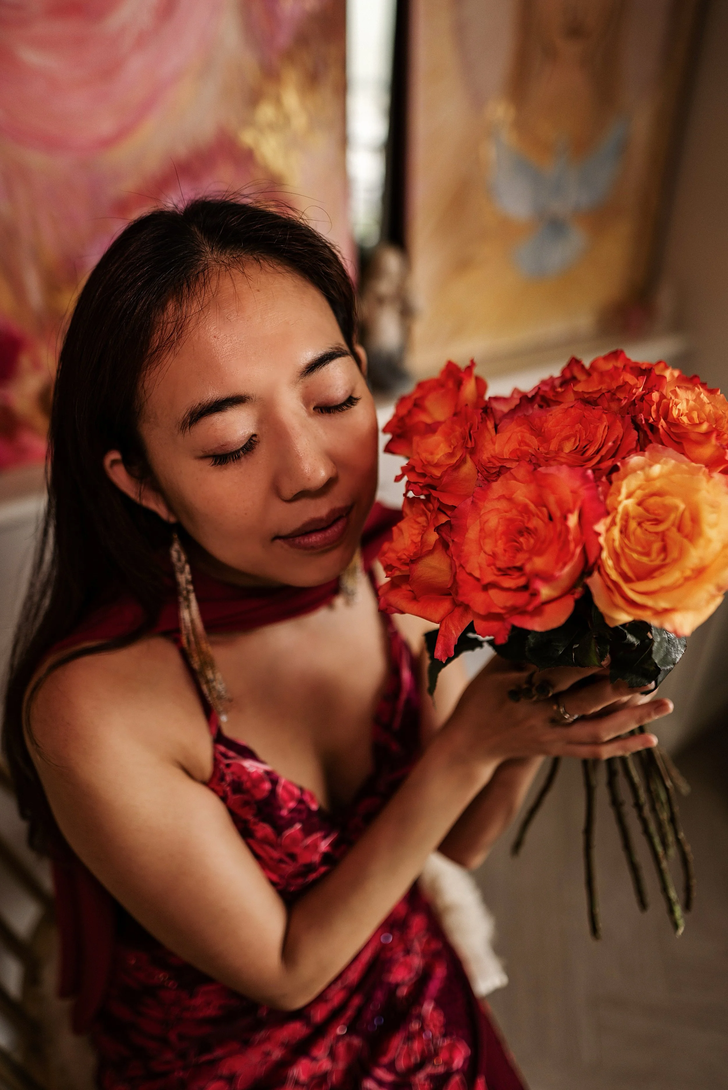 a woman with closed eyes holding a boquet of orange roses, illustrating 1:1 womb healing sessions in bangkok thailand