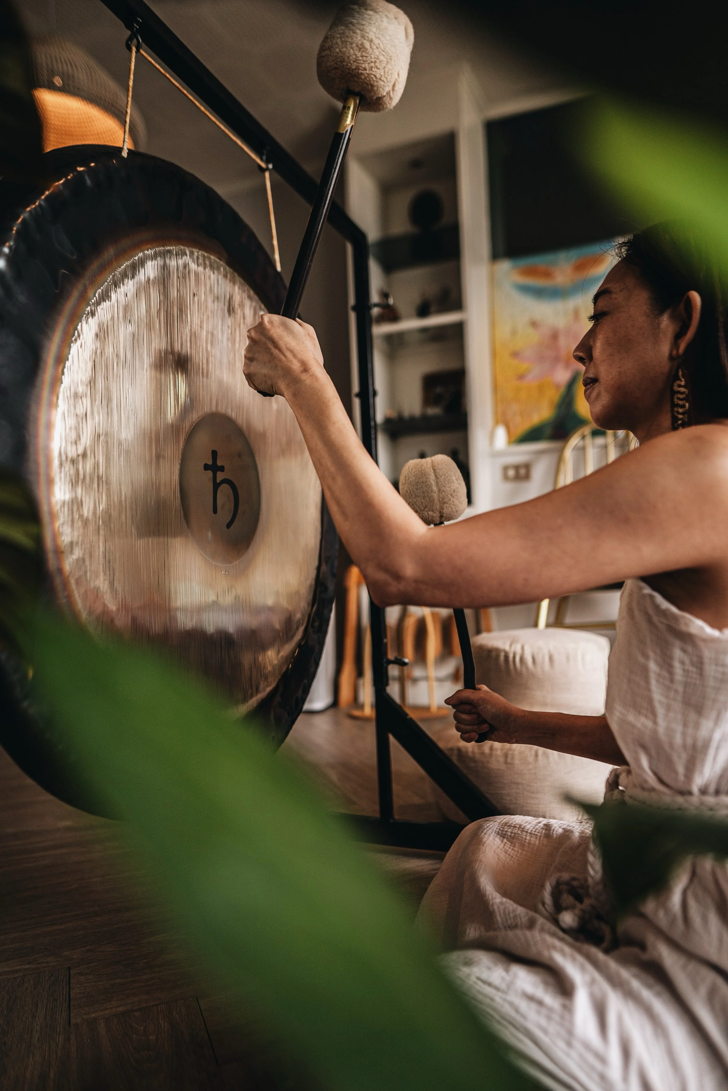 A woman playing a gong illustrating sound healing sessions in Bangkok, Thailand