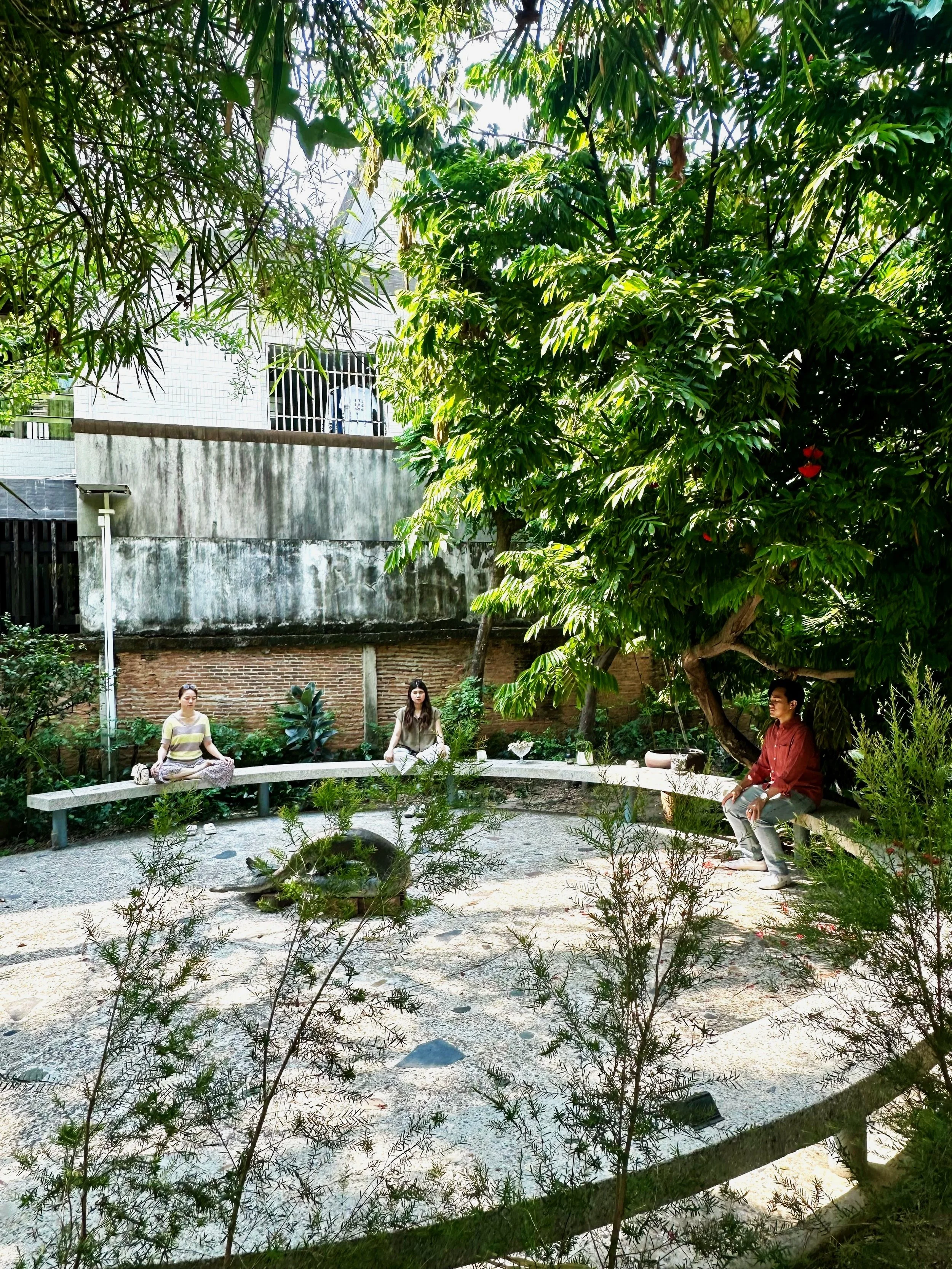 a group of three students sitting on a circular bench in meditation